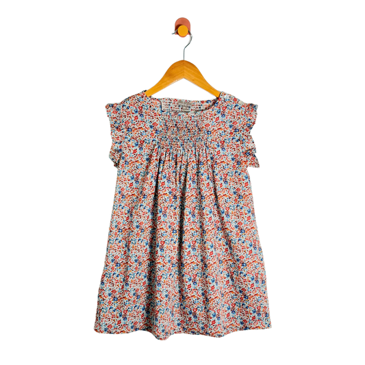 A children's short-sleeve dress with a dense multicolor floral print, hanging on a wooden hanger against a plain white background.