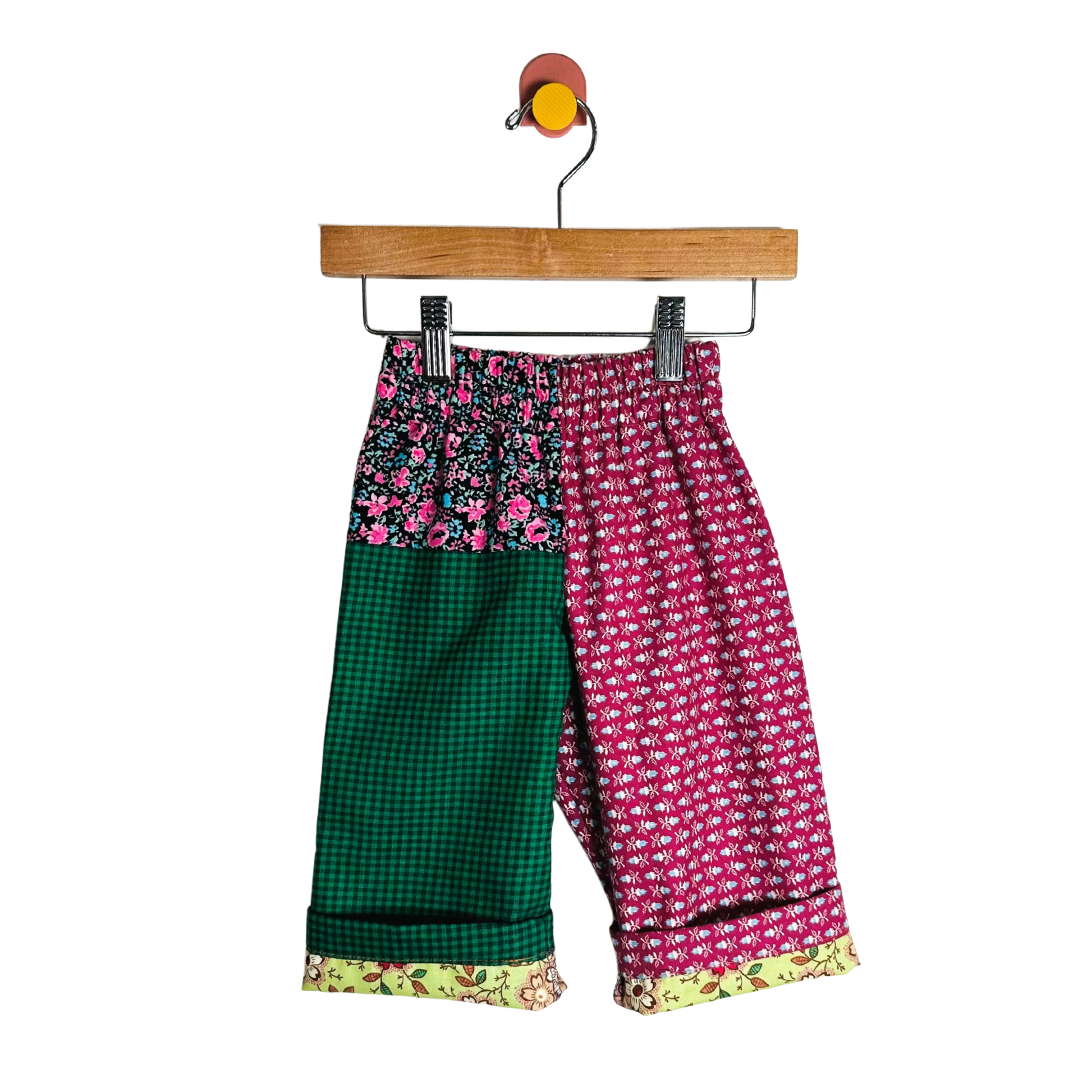 Colorful patterned pants on a hanger against a white background
