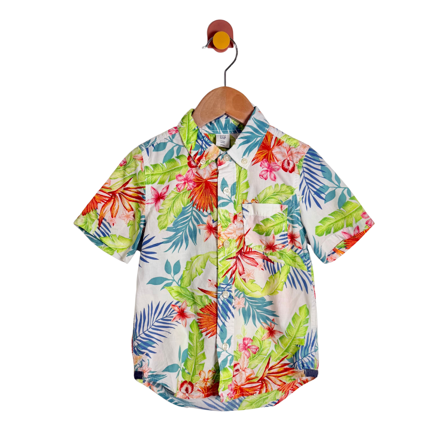 A short-sleeve button-up shirt with a vibrant tropical floral and leaf print, hanging on a wooden hanger against a plain white background.