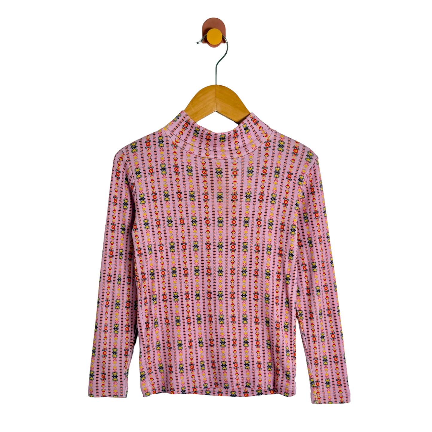 A pink long-sleeve mock neck top with a vertical multicolor geometric pattern, hanging on a wooden hanger against a white background.