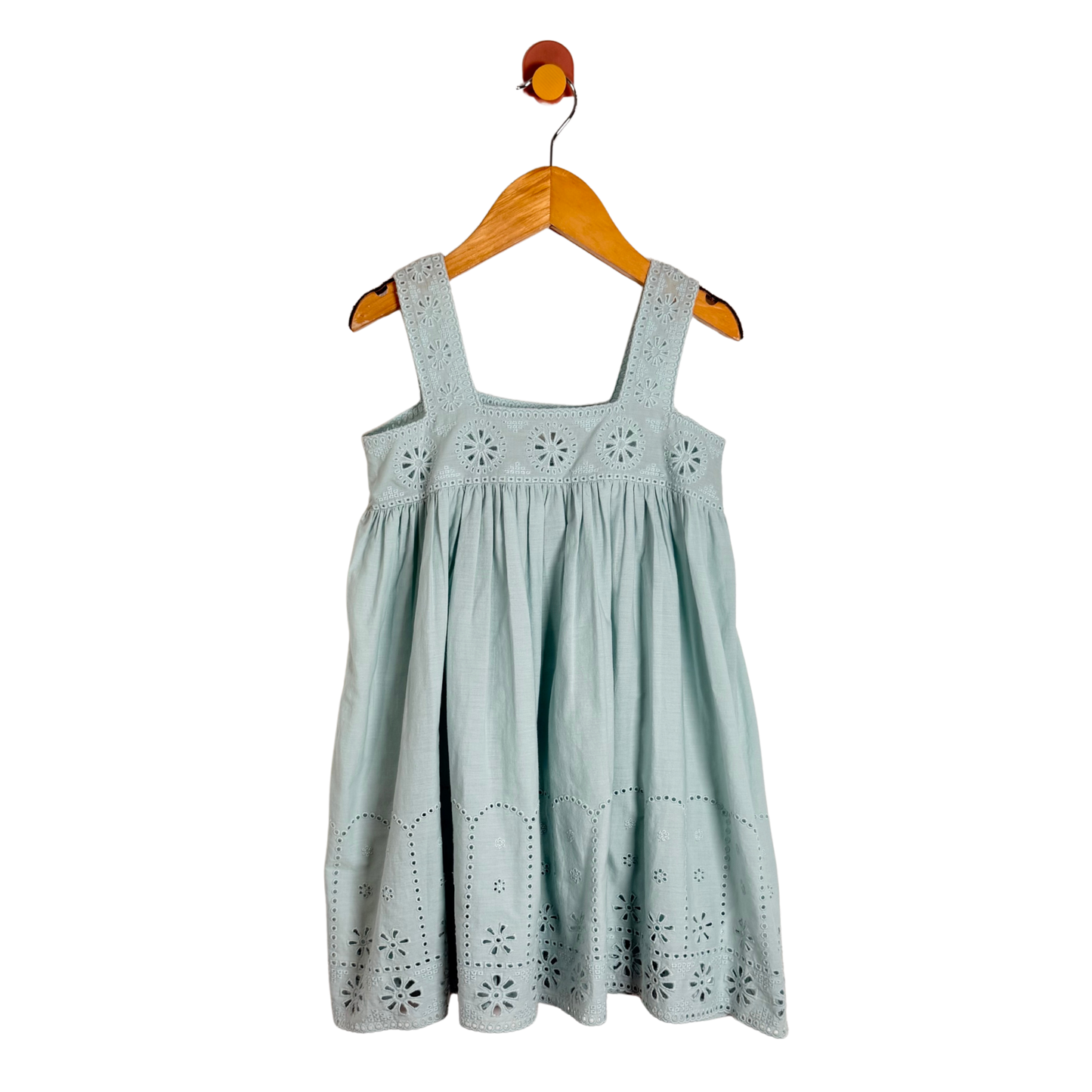 A light sage green eyelet cotton dress for kids, hanging on a wooden hanger against a solid white background.