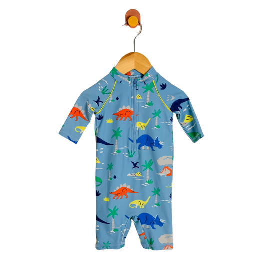 A baby long-sleeve one-piece swimsuit or sleep suit in light blue, featuring a colorful dinosaur print, hanging on a wooden hanger against a white background.