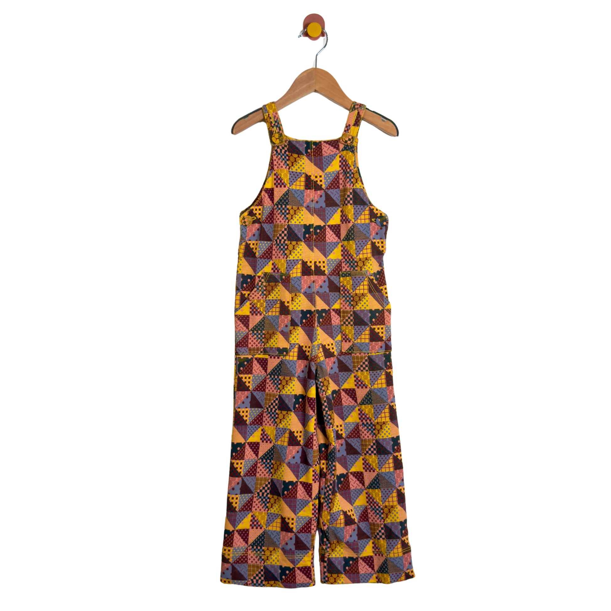 A sleeveless wide-leg jumpsuit with a colorful geometric patchwork print, hanging on a wooden hanger against a plain white background.