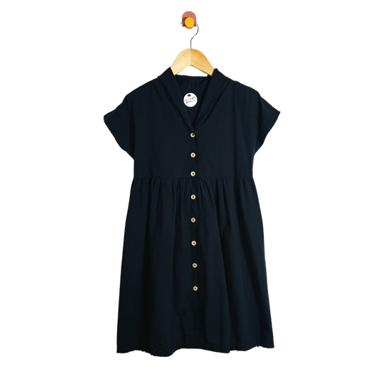 Black dress with buttons on a hanger against a white background