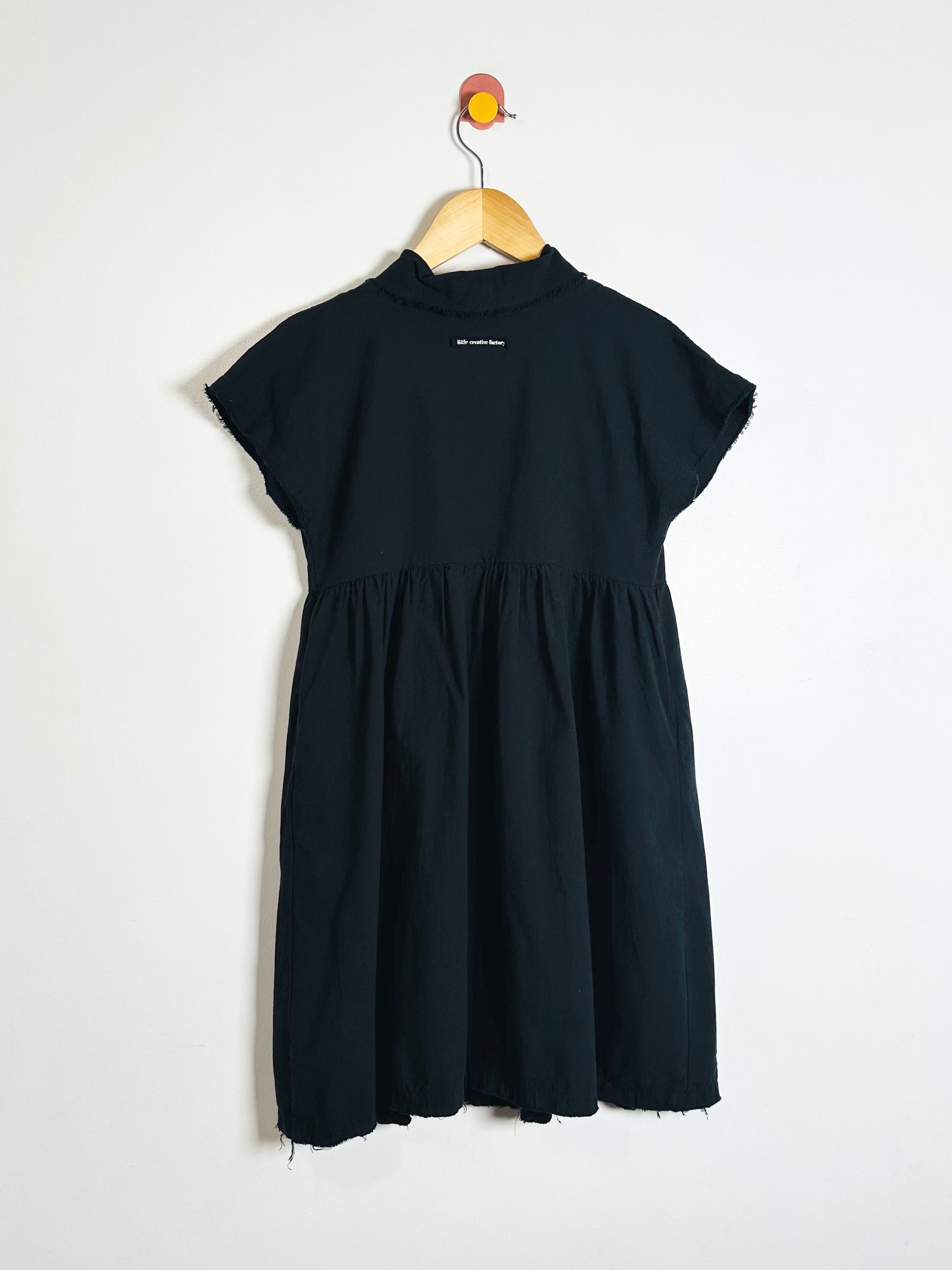 Black dress on a hanger against a white background