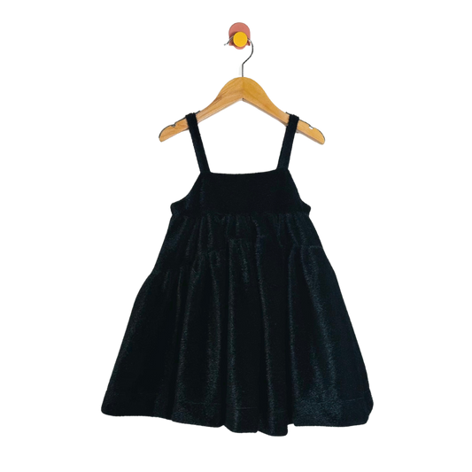 Black velvet dress on a wooden hanger against a white background