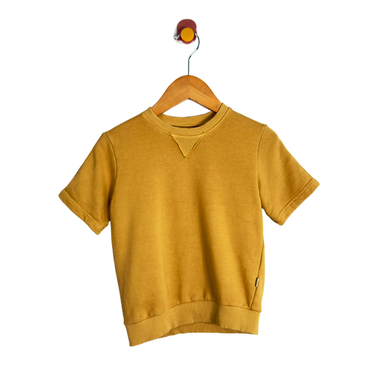 A mustard yellow short-sleeve crewneck sweatshirt hanging on a wooden hanger with a wall hook, shown against a solid white background.