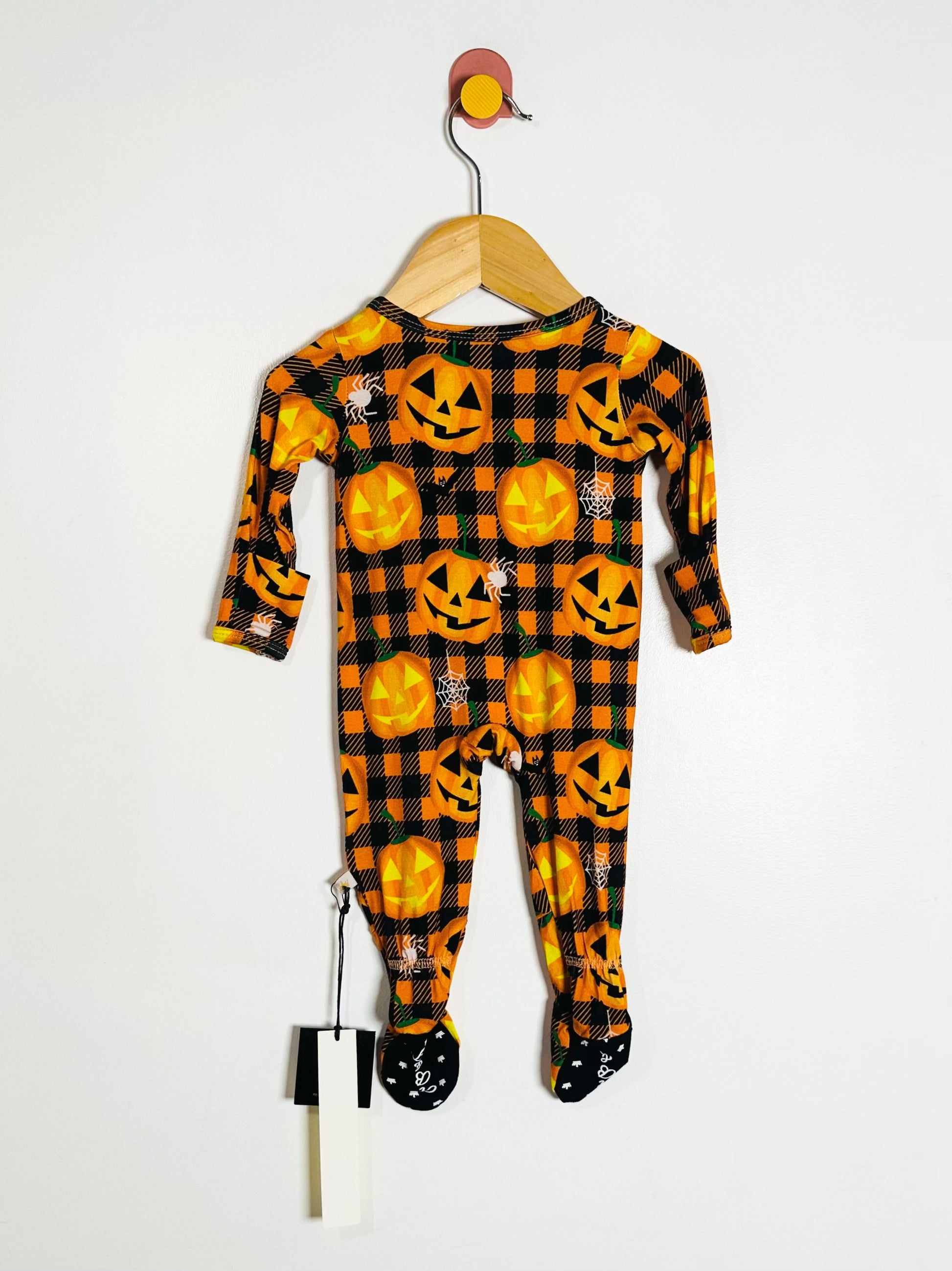 Halloween-themed baby onesie with pumpkins and plaid pattern on a hanger against a white background.