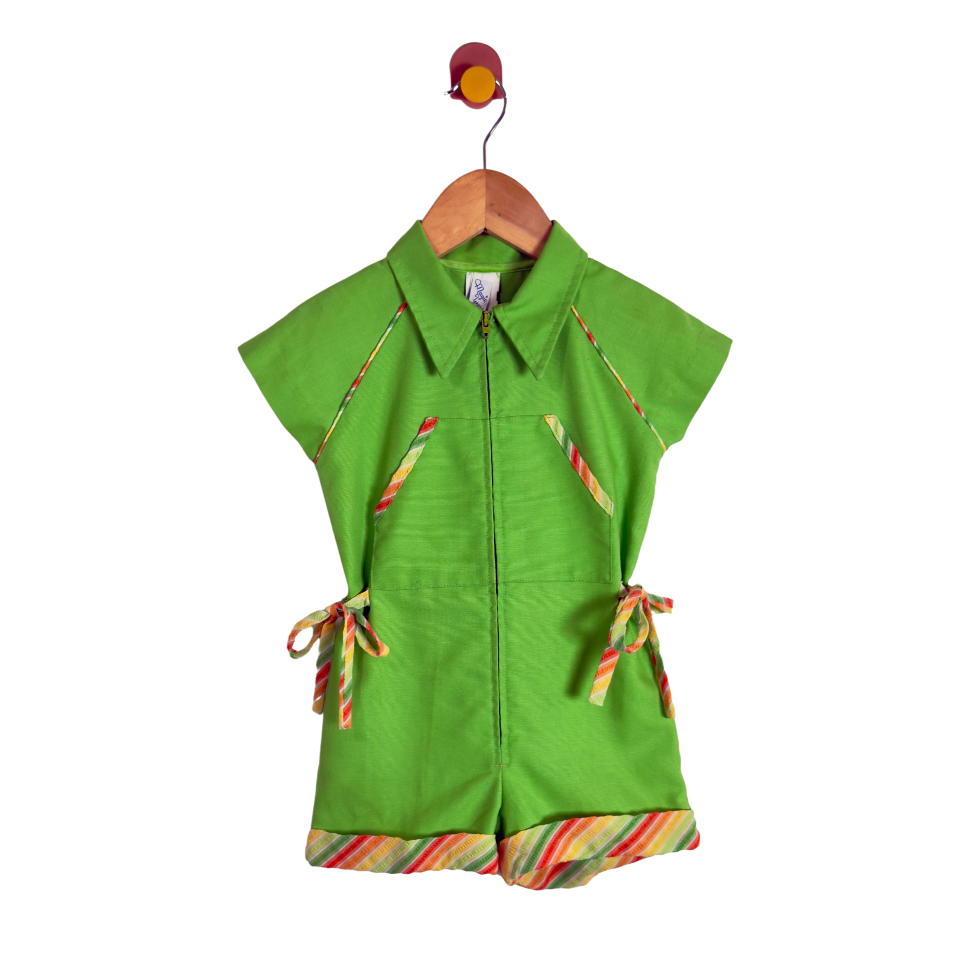 A bright green short-sleeve collared romper or jumpsuit hanging on a wooden hanger against a plain white background. The garment has colorful striped trim details along the pockets, ties, and hem, and a front zipper.