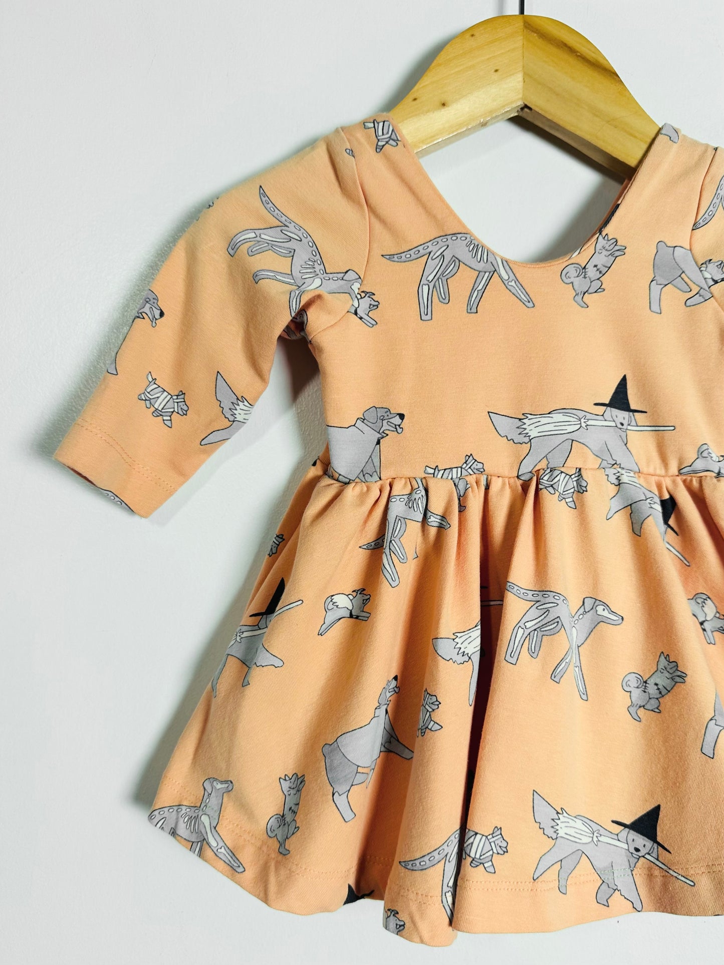 Children's dress with dog pattern on a hanger against a white background
