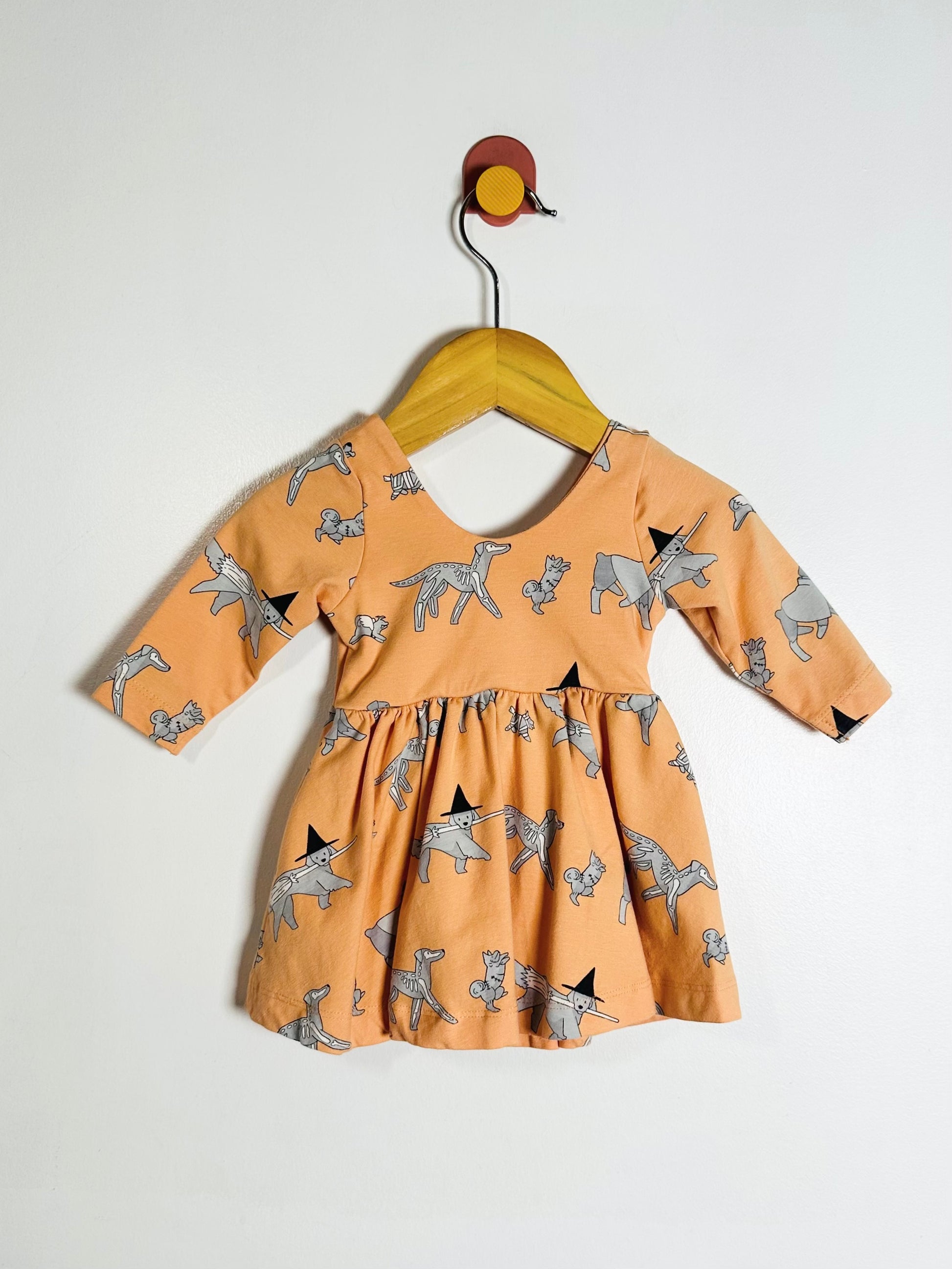Children's dress with dog pattern on a hanger against a white background