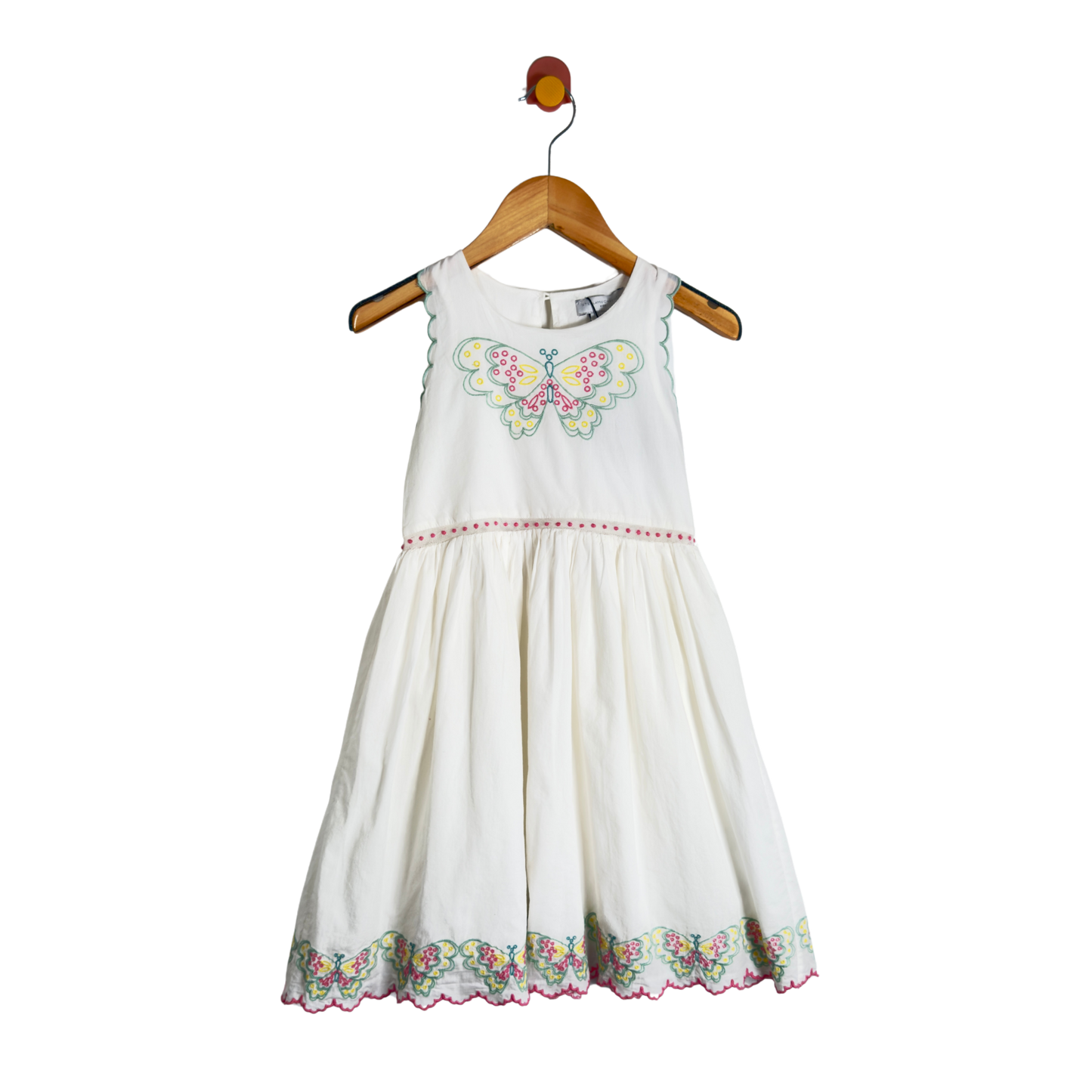 A sleeveless white children's dress with a colorful butterfly embroidery on the chest and a floral embroidered hem, hanging on a wooden hanger against a white background.