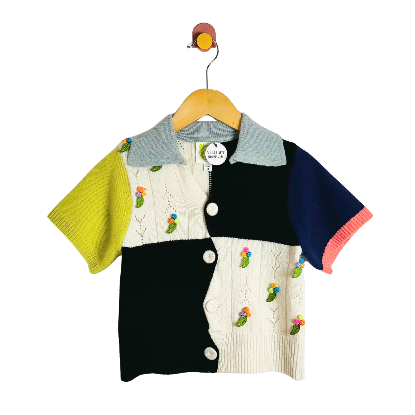 Colorful children's cardigan with embroidered designs on a hanger against a white background