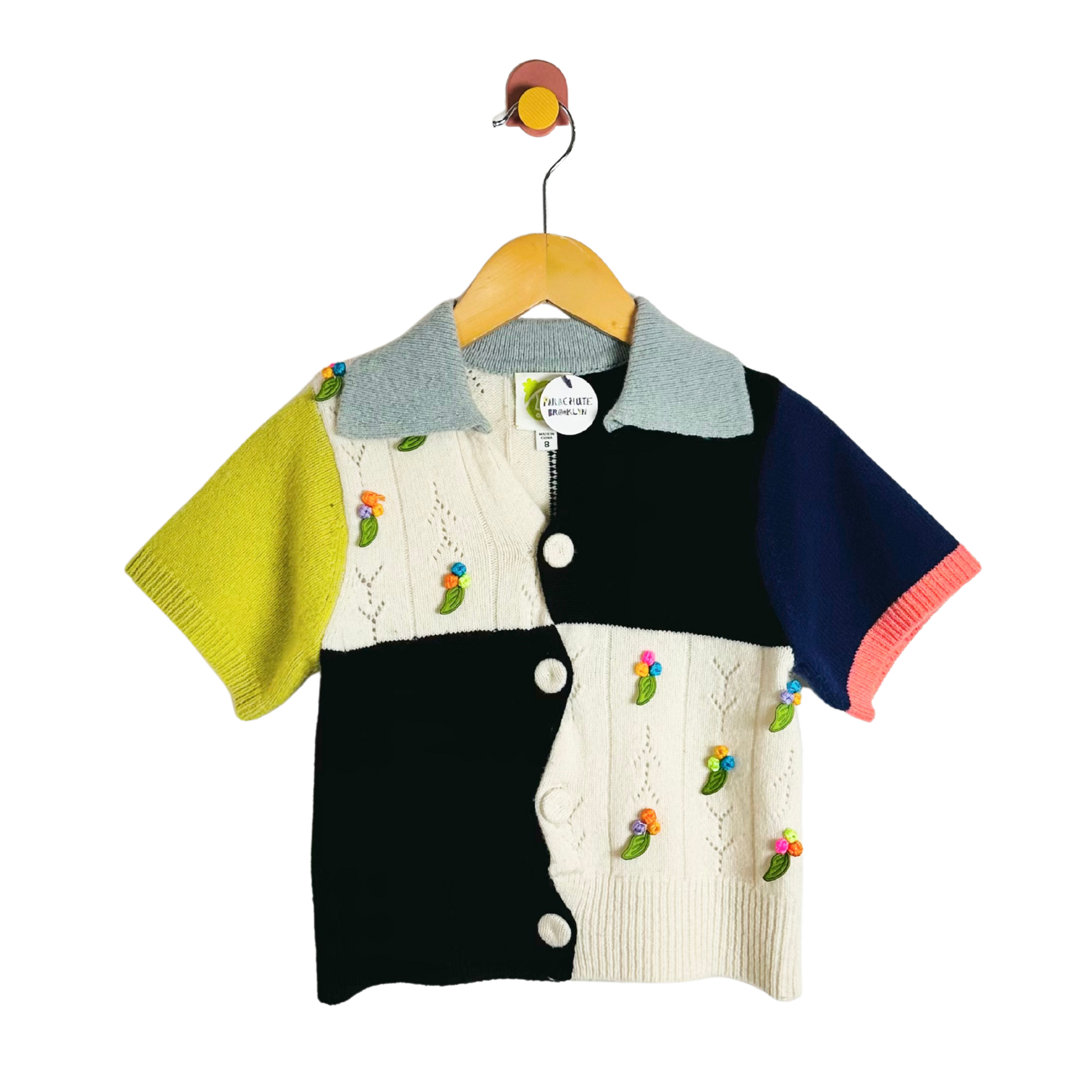 Colorful children's cardigan with embroidered designs on a hanger against a white background