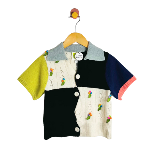 Colorful children's cardigan with embroidered designs on a hanger against a white background
