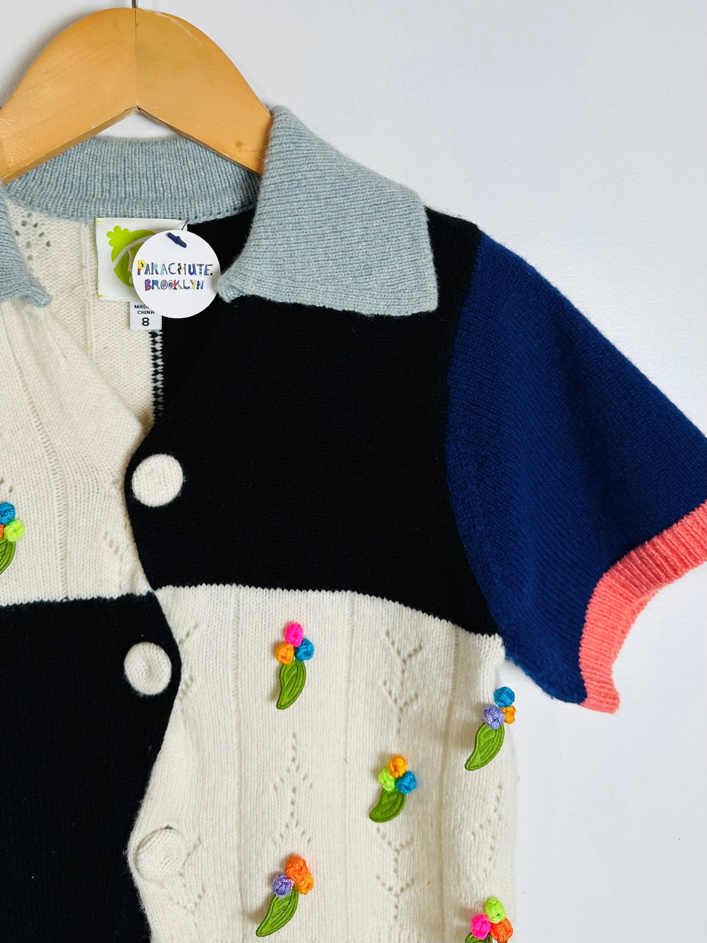 Color-blocked sweater with floral embroidery on a hanger