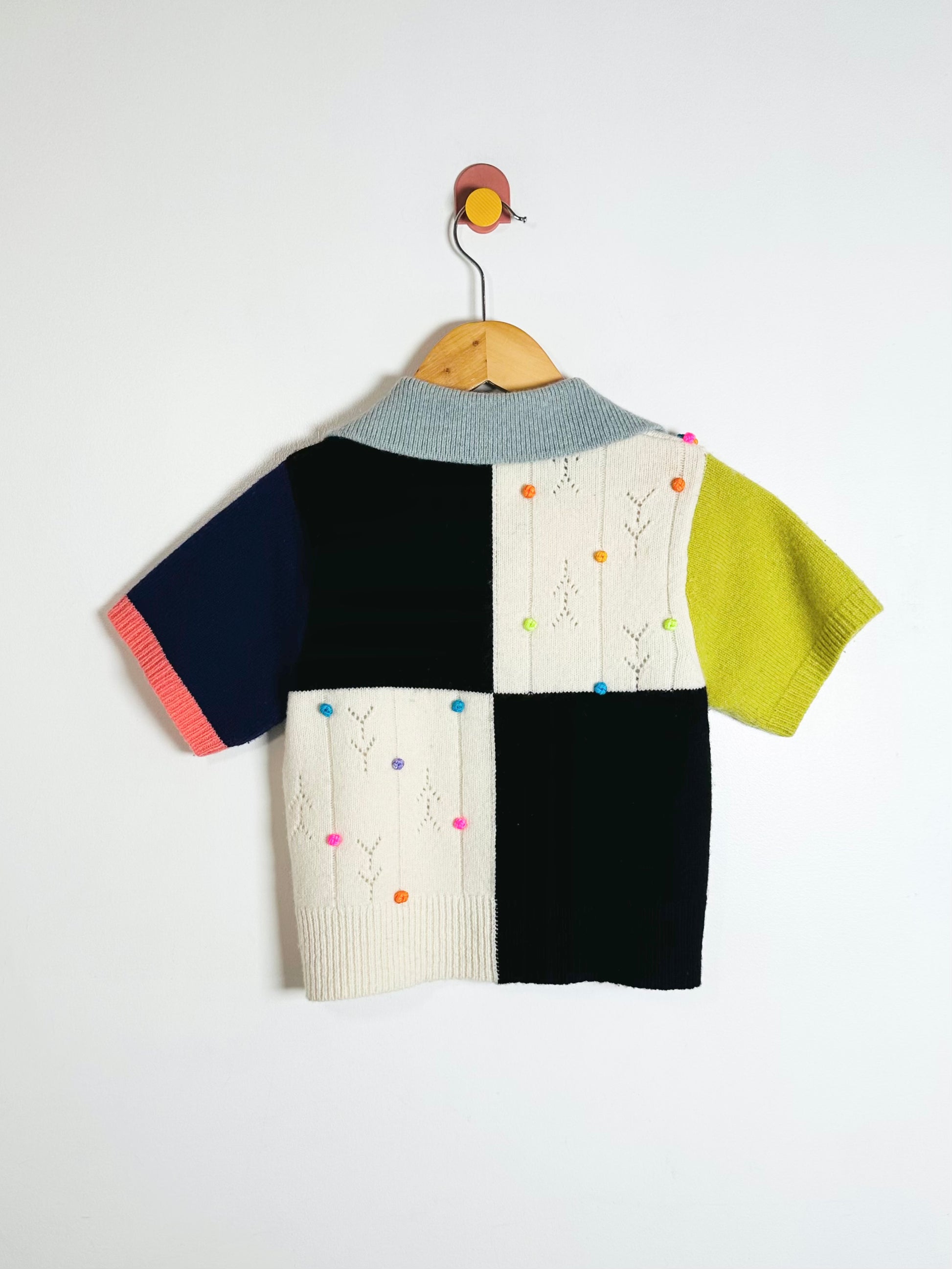 Colorful children's sweater on a hanger against a white background