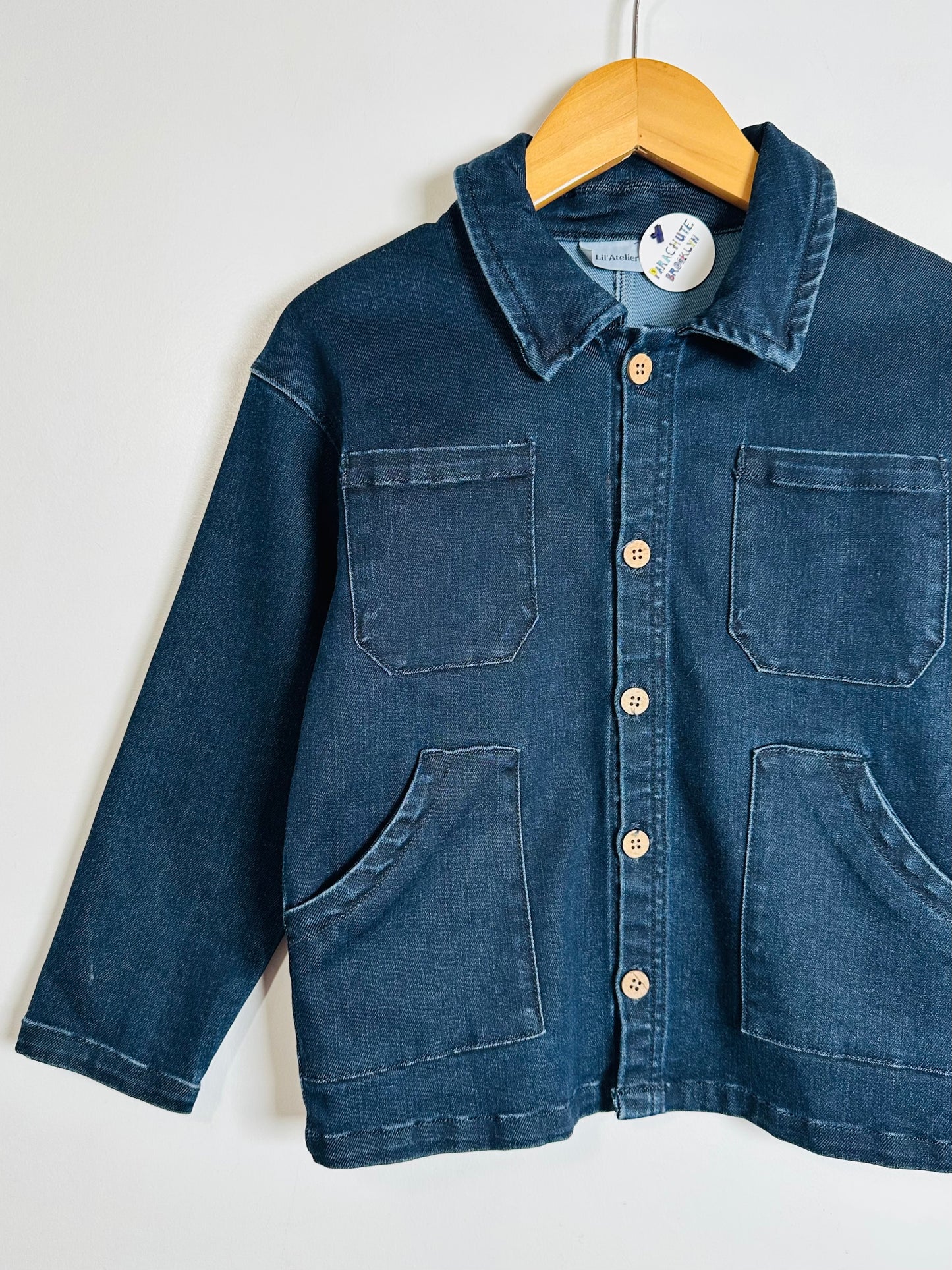 Blue denim jacket on a hanger against a white background