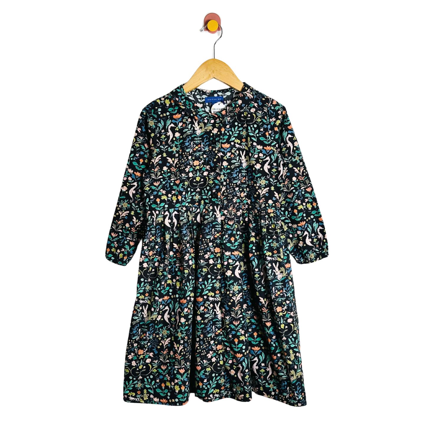 Floral patterned dress on a hanger against a white background