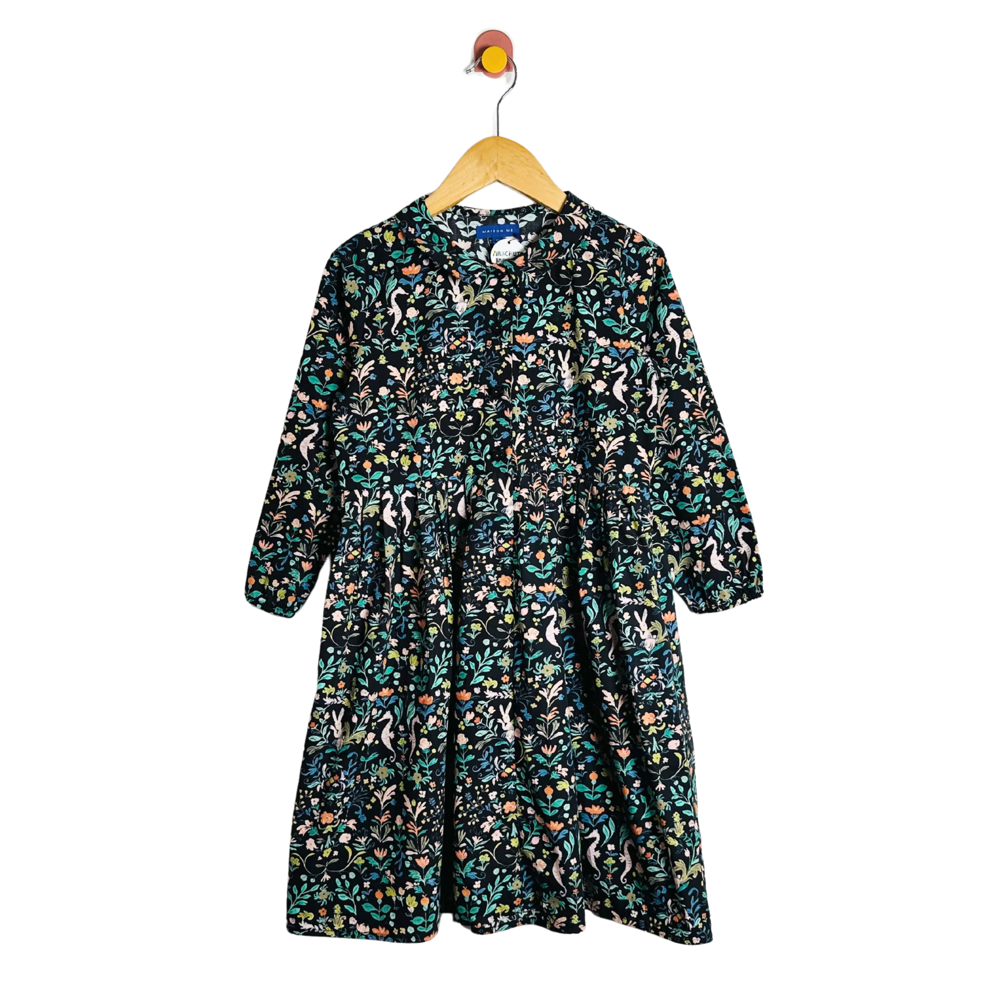 Floral patterned dress on a hanger against a white background