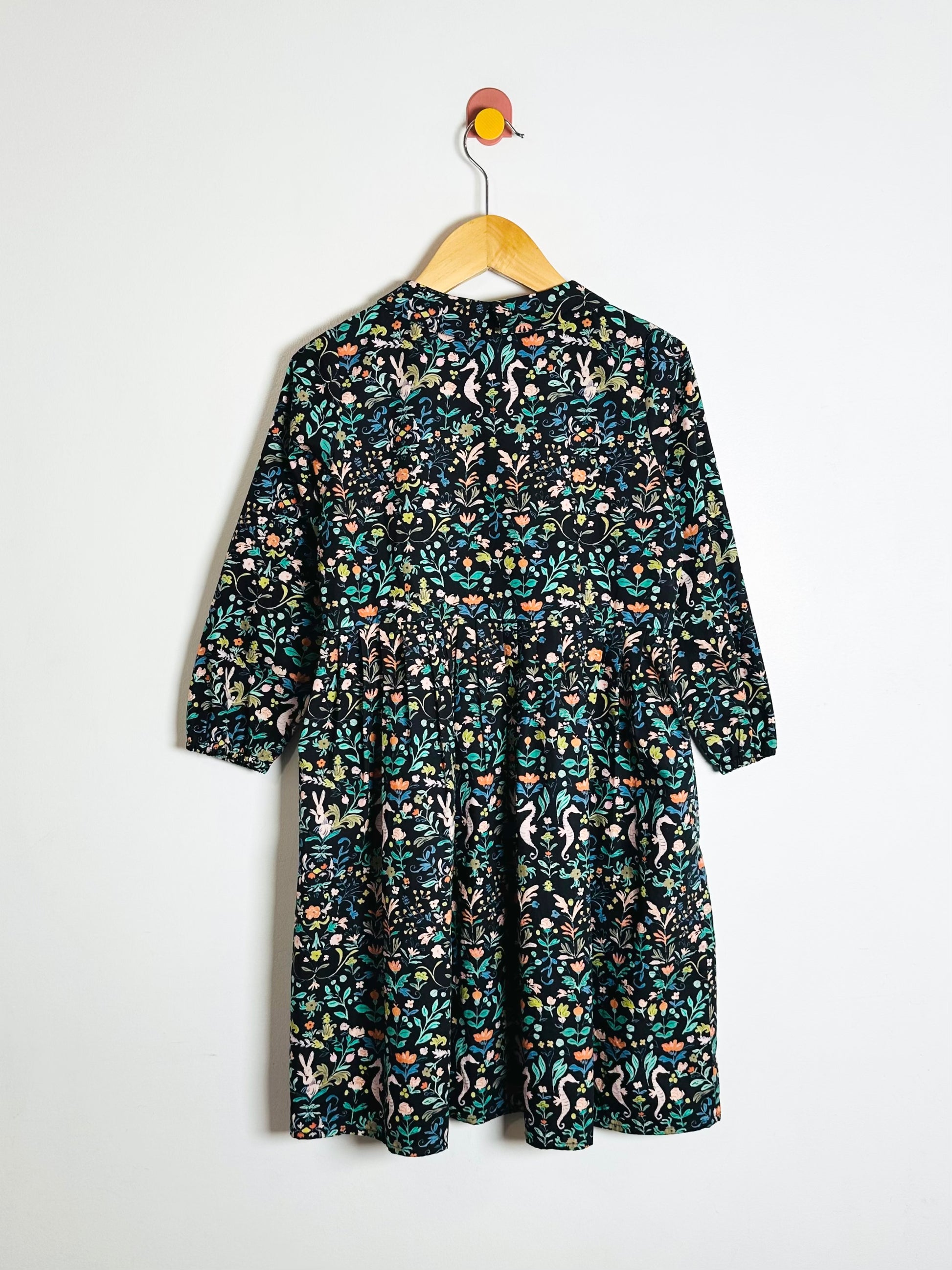 Floral patterned dress on a hanger against a white background