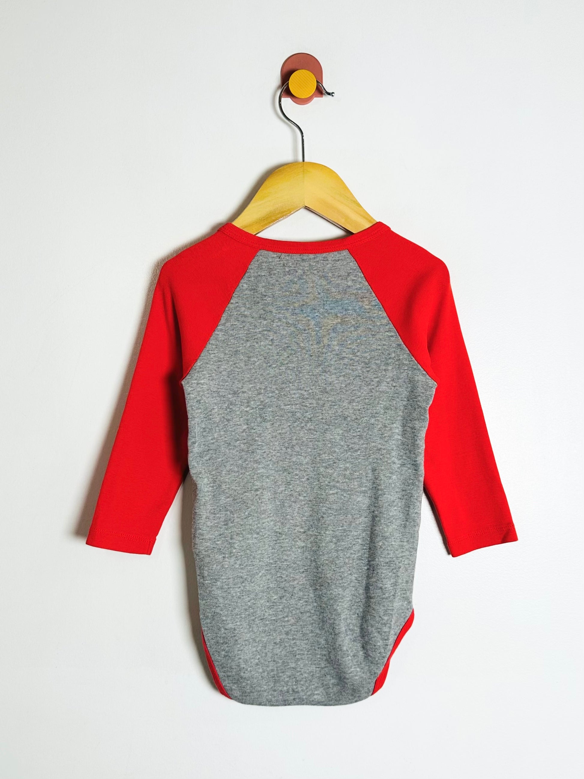 Gray and red long-sleeve baby bodysuit on a hanger against a white background