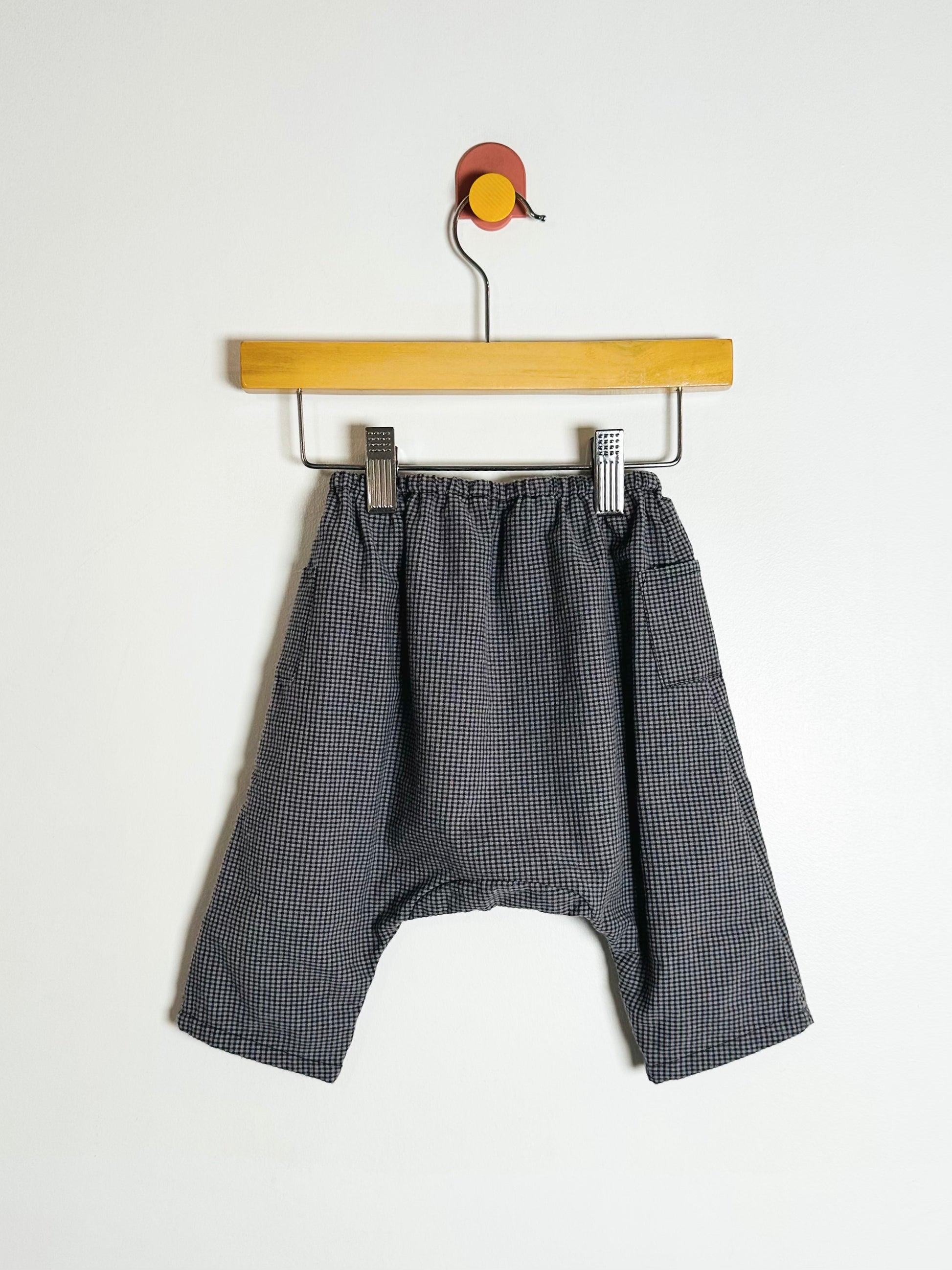Gray checkered shorts on a wooden hanger against a white background