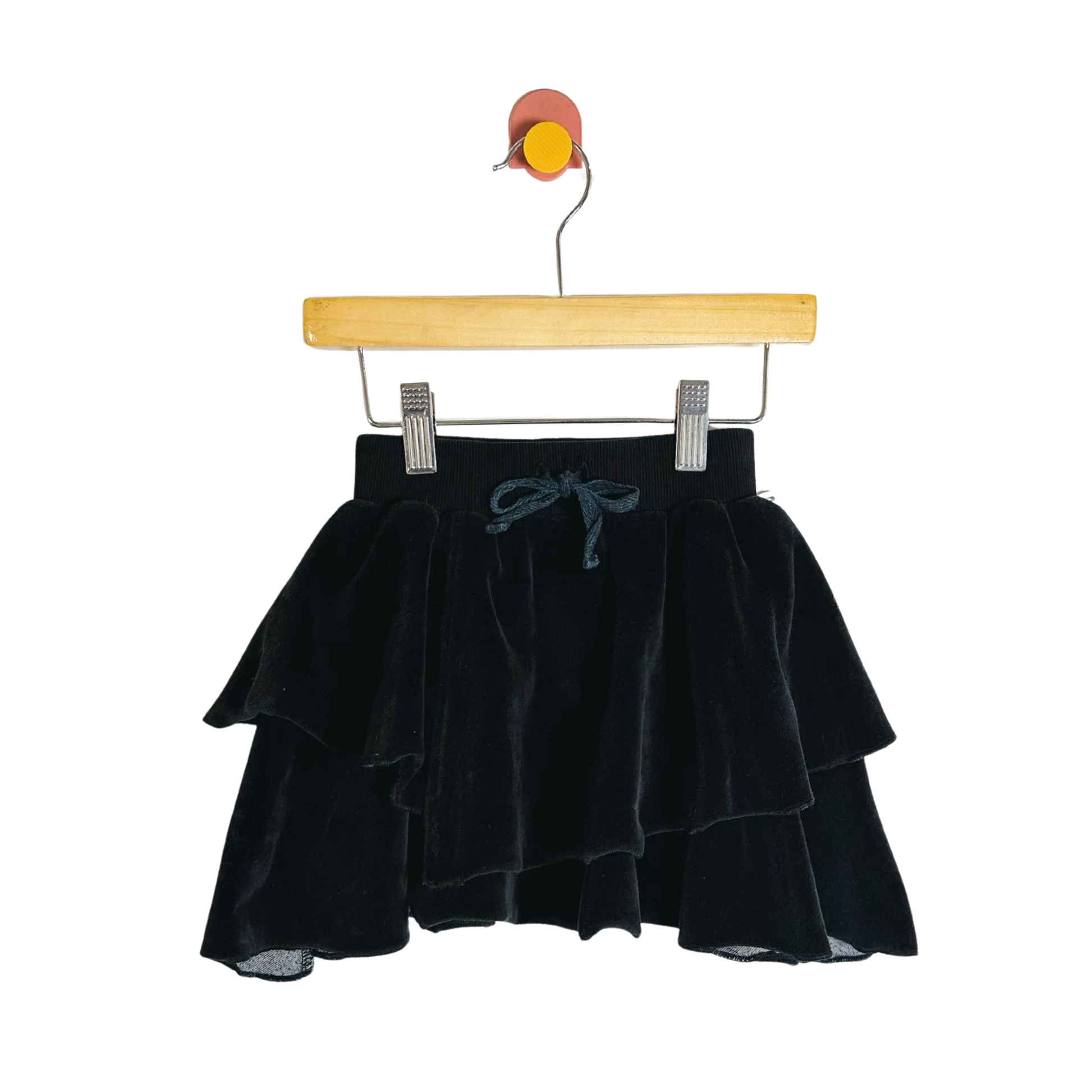 Black velvet skirt on a wooden hanger against a white background