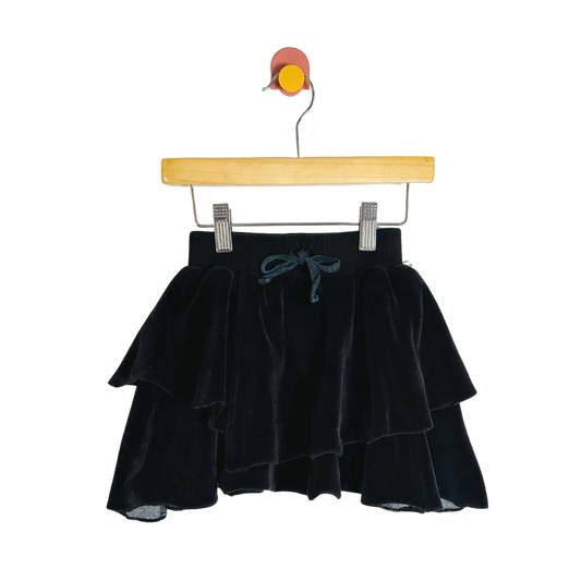 Black velvet skirt on a wooden hanger against a white background