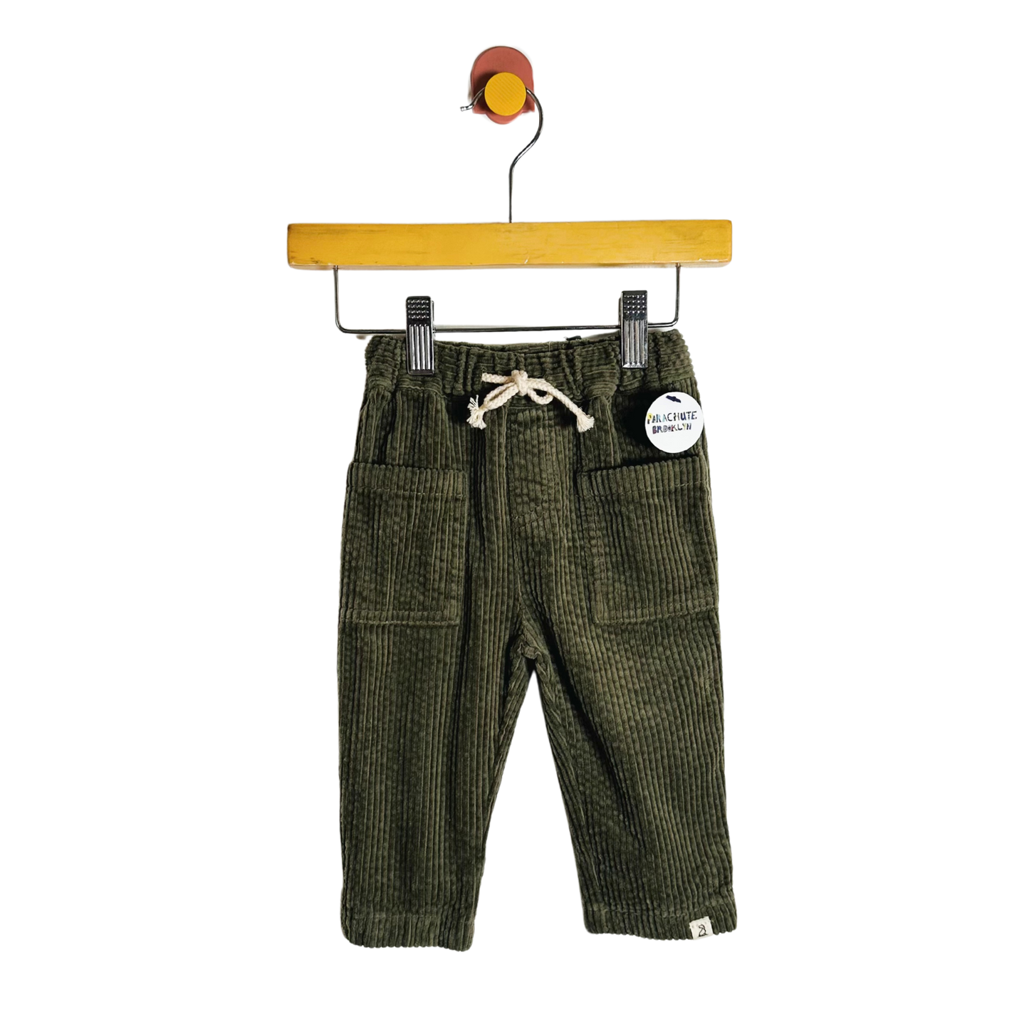 Green corduroy pants on a hanger with a white background