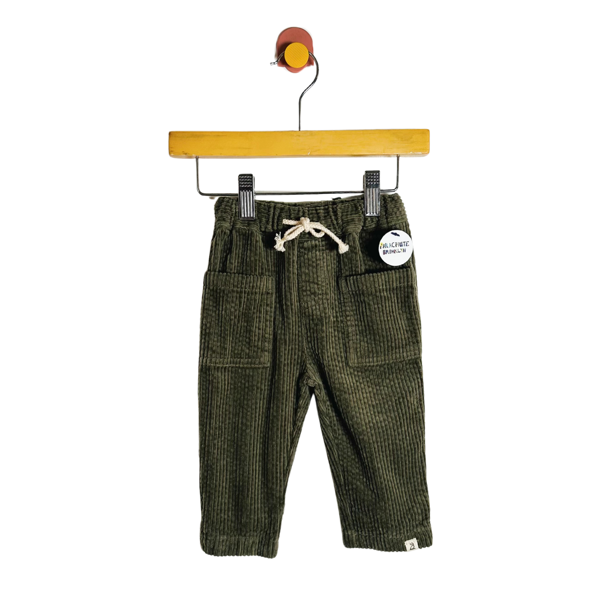 Green corduroy pants on a hanger with a white background
