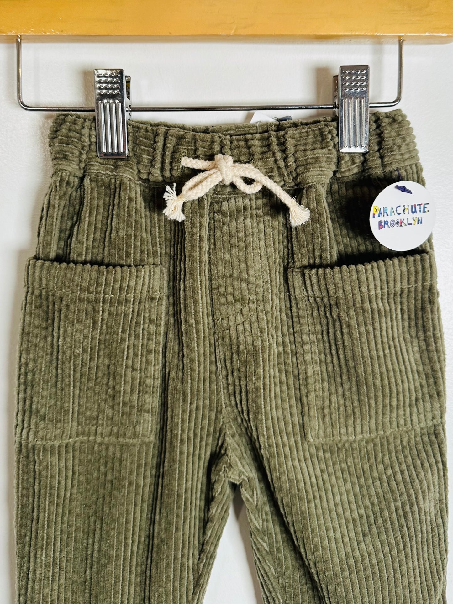 Green corduroy pants with a label on a white background