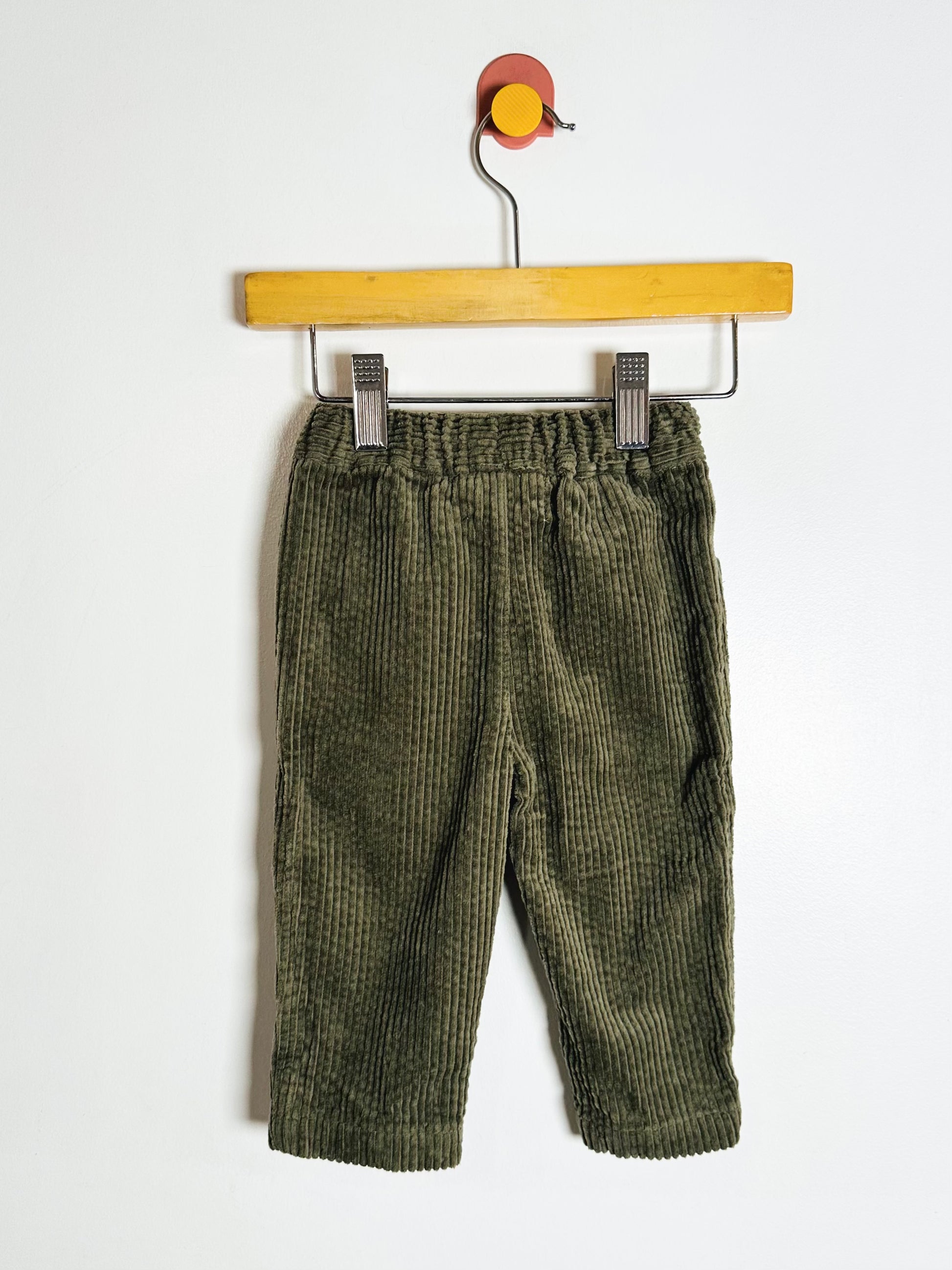 Green checkered pants on a hanger against a white background