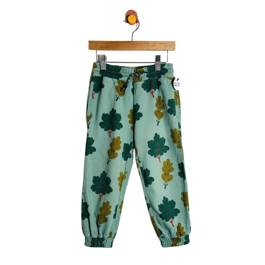 Green pants with leaf pattern on a hanger against a white background