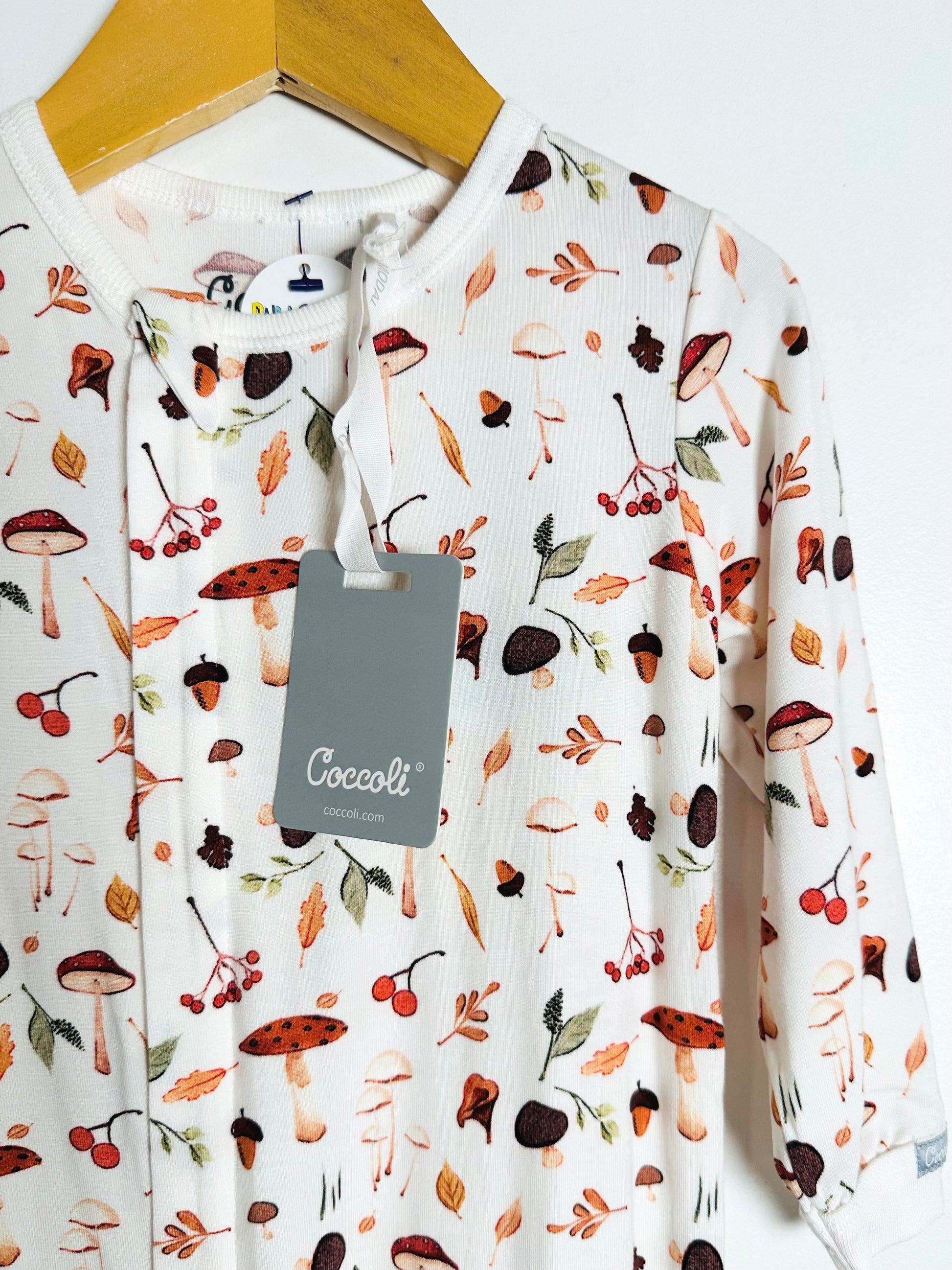 Long-sleeve shirt with autumnal pattern on a hanger, featuring a Coccoli tag.