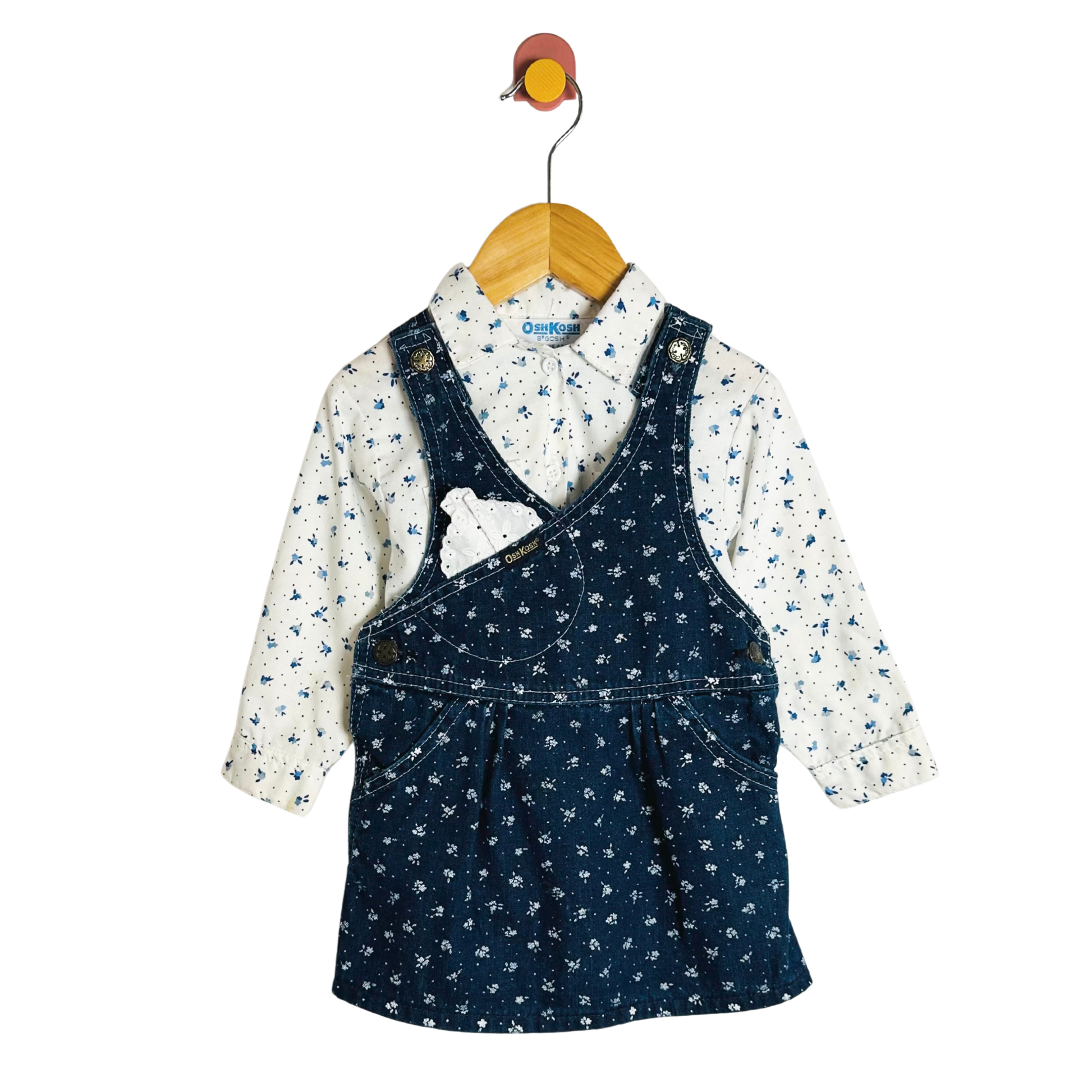 Children's outfit with navy pinafore and floral shirt on a hanger