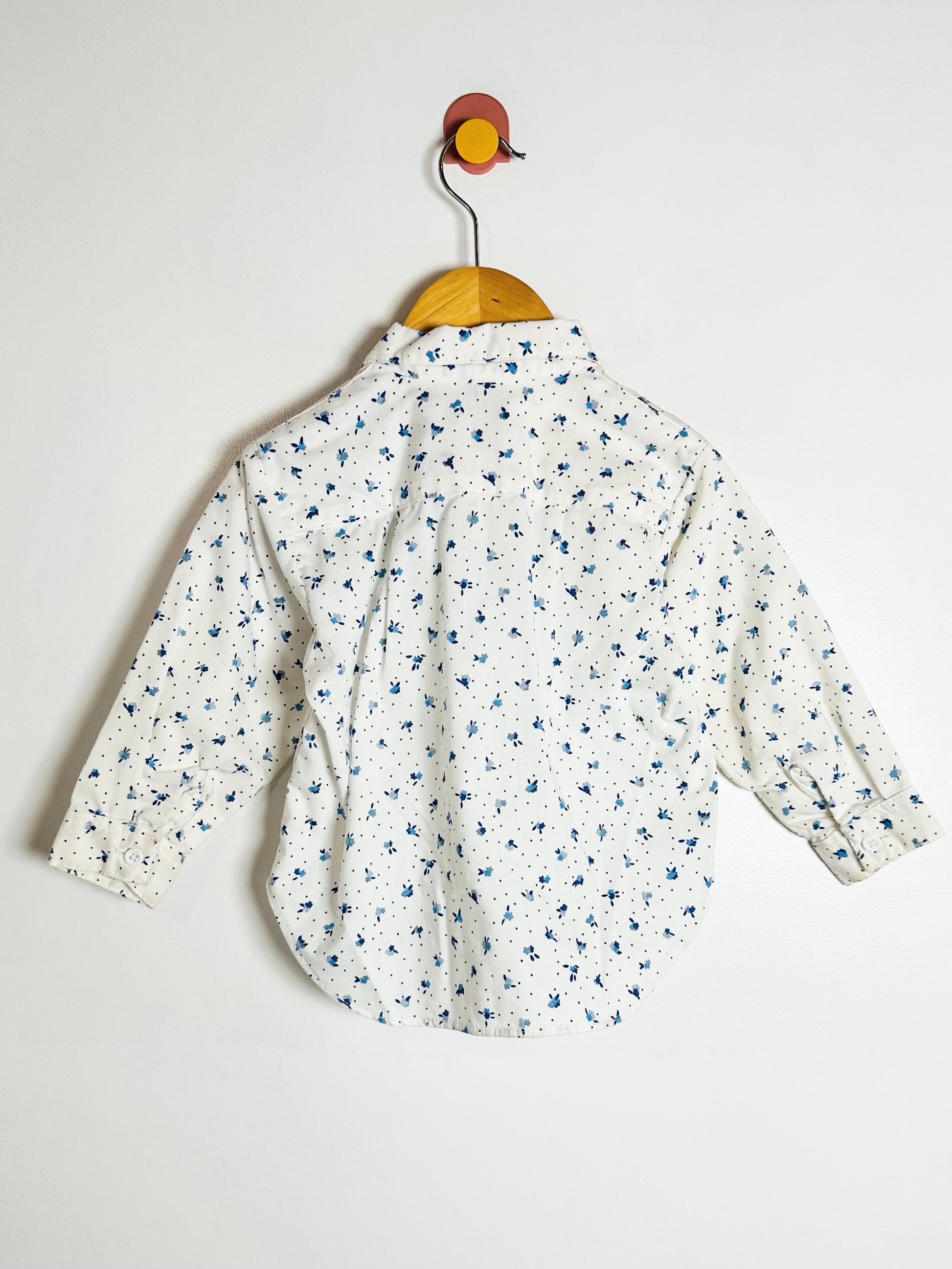 Floral-patterned shirt on a hanger against a white background