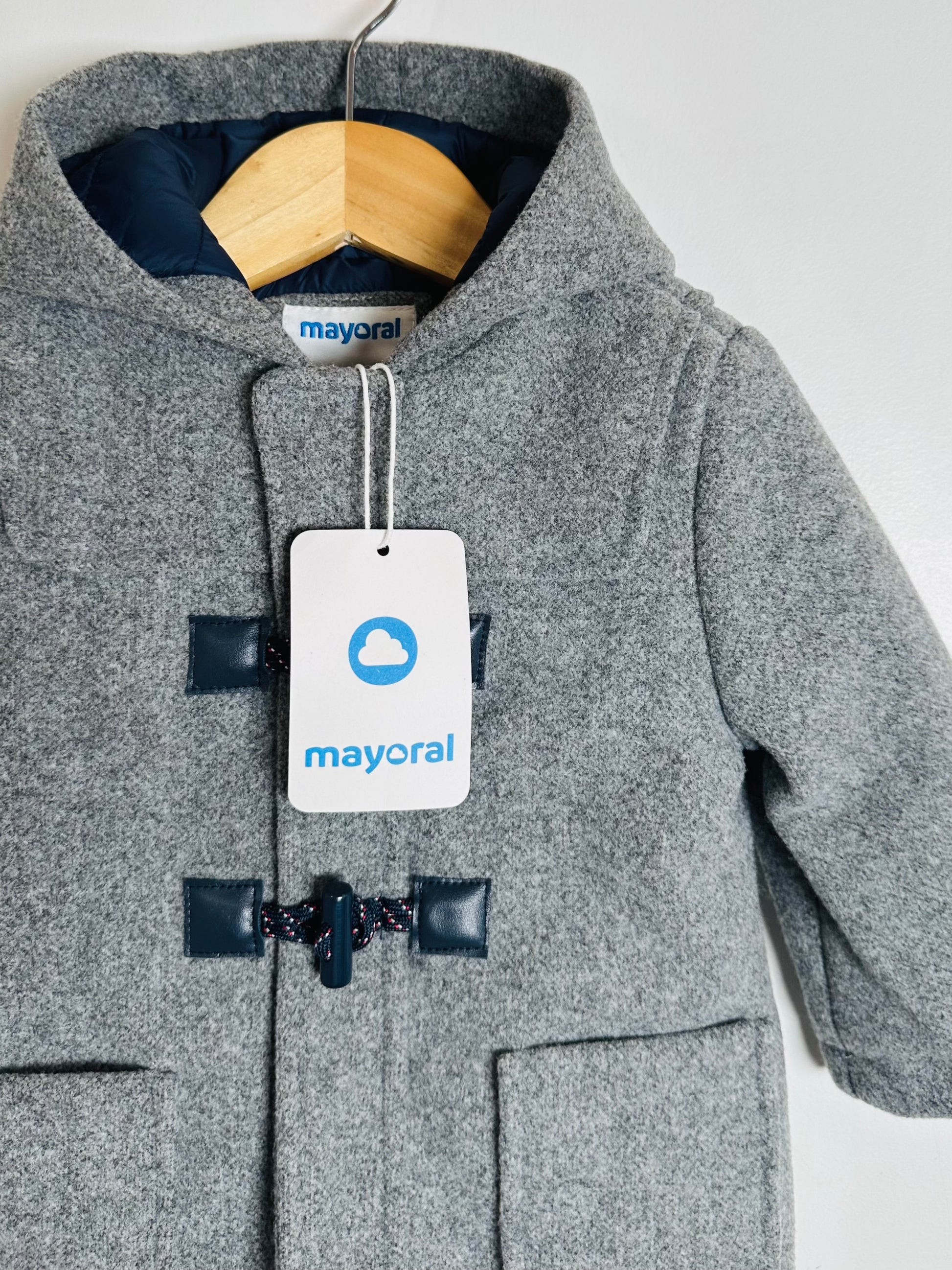 Gray coat with navy buttons and a Mayoral tag on a white background