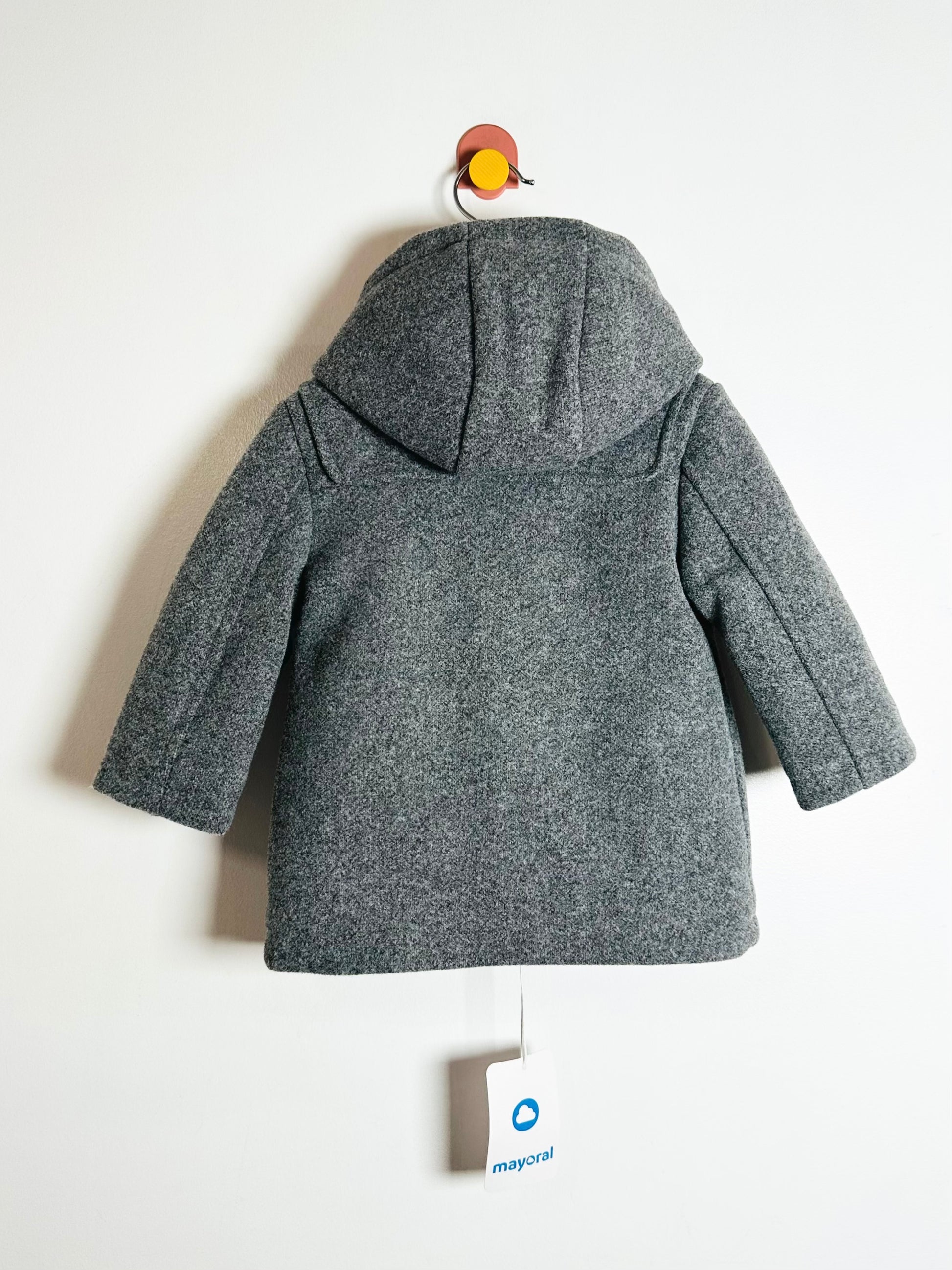 Gray children's coat on a hanger with a visible brand tag against a white background