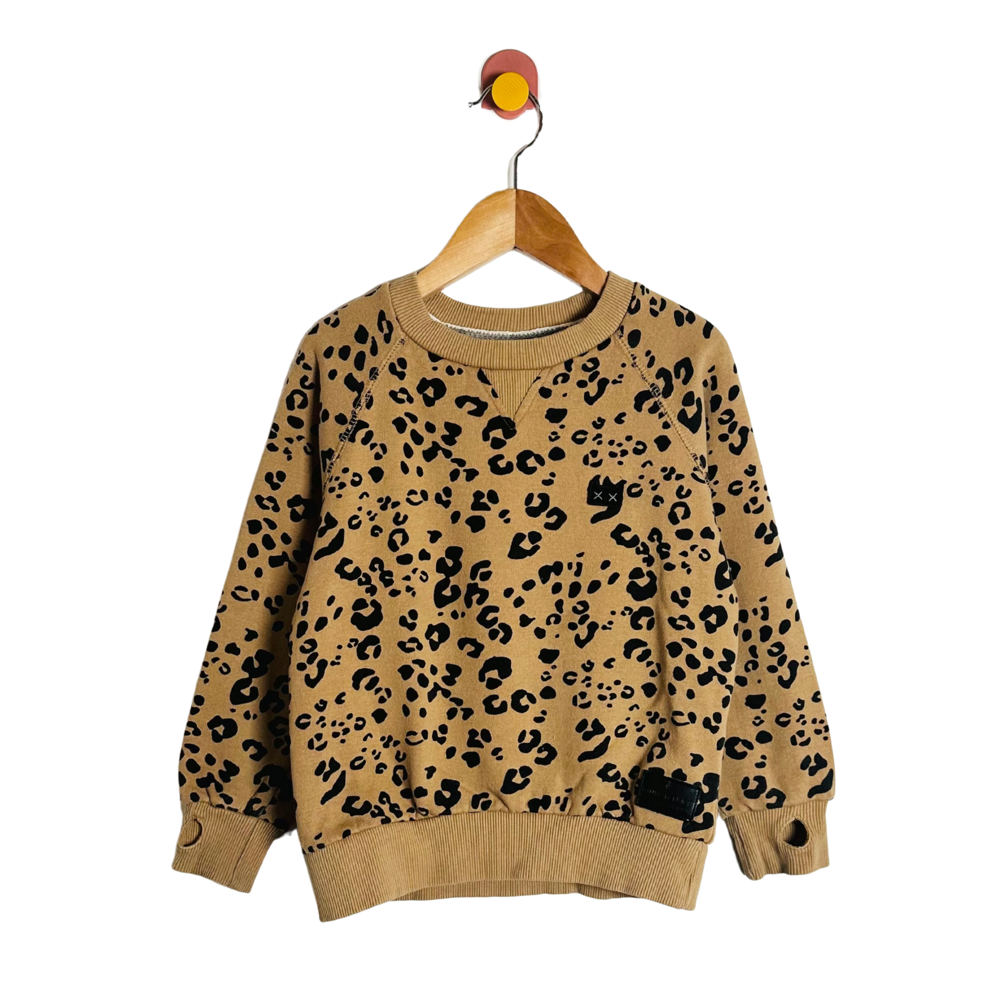 Beige sweater with black leopard print on a wooden hanger against a white background