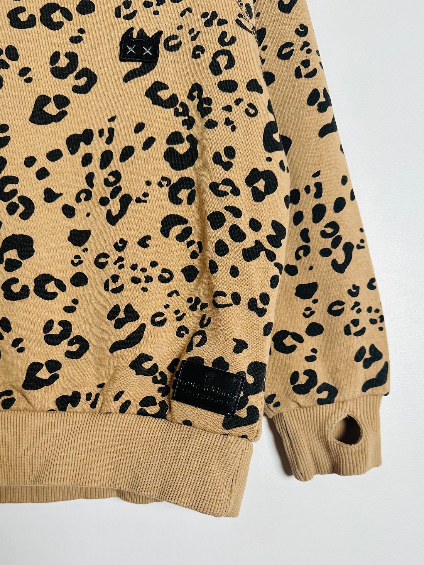 Beige sweatshirt with black leopard print pattern on a white background