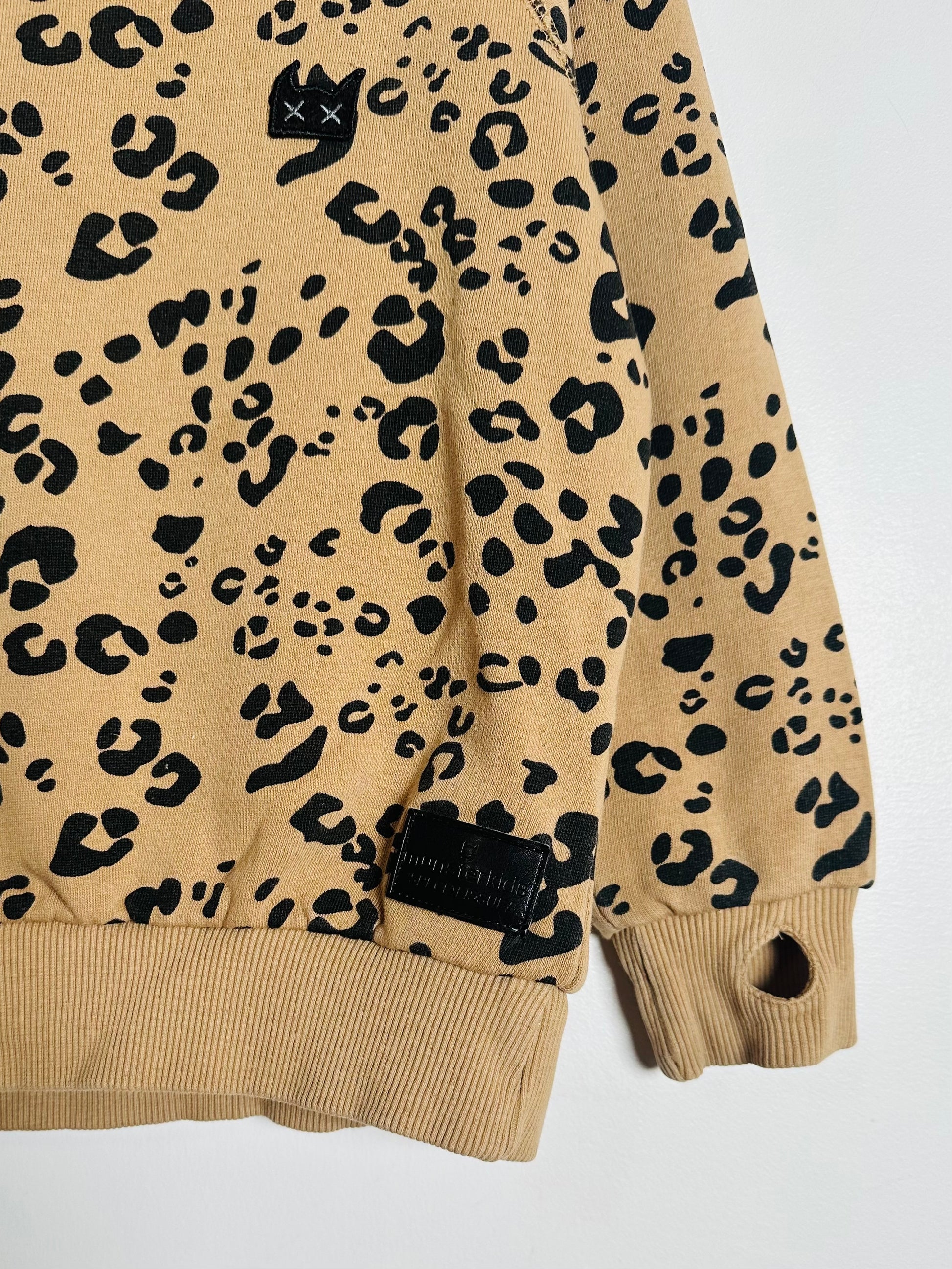 Beige sweatshirt with black leopard print pattern on a white background