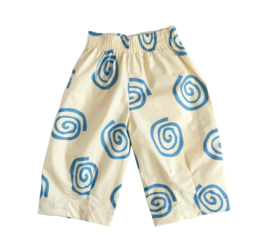 A pair of cream-colored pants with a blue spiral pattern, featuring an elastic waistband, shown against a plain white background.