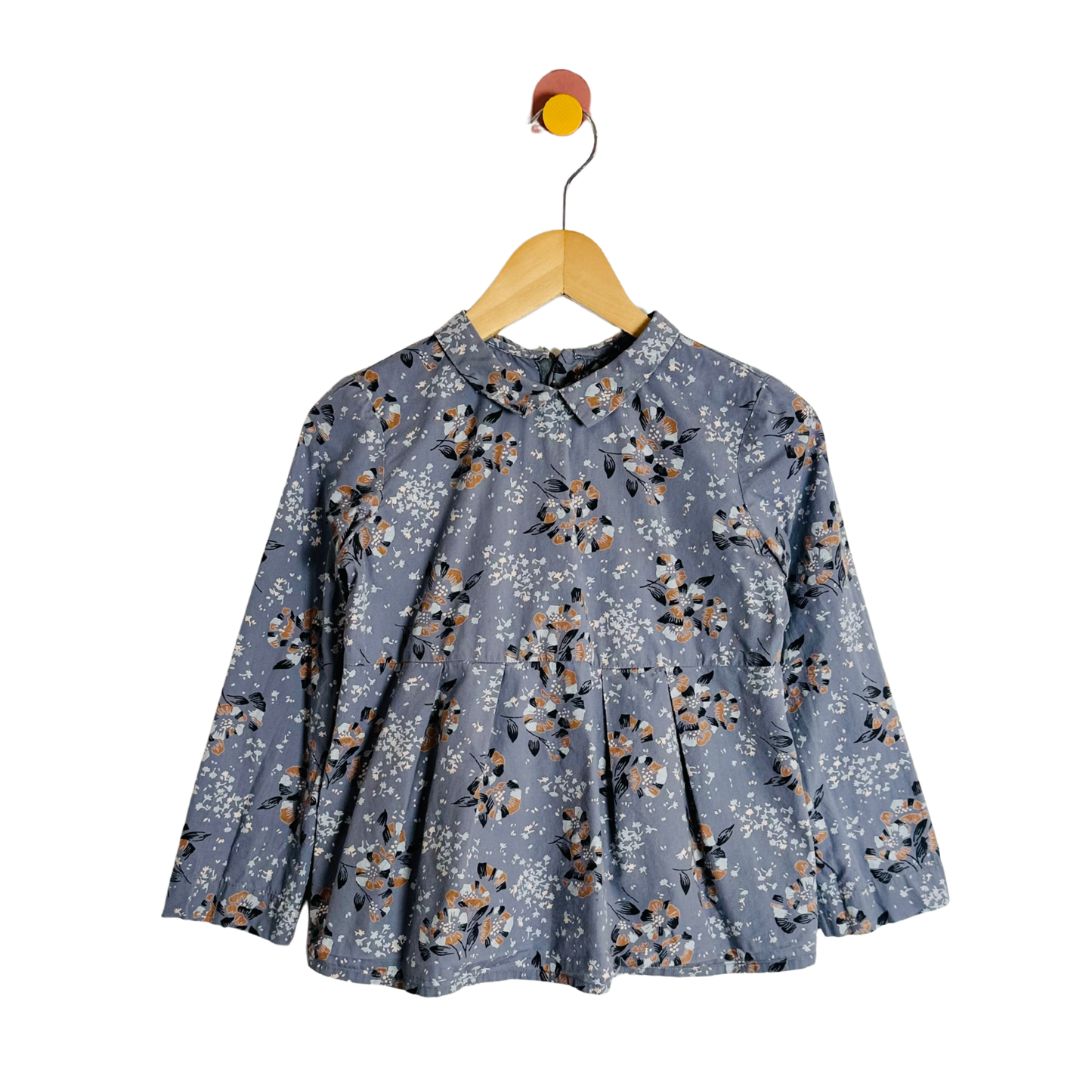 Floral patterned blouse on a wooden hanger against a white background