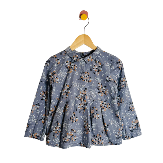 Floral patterned blouse on a wooden hanger against a white background