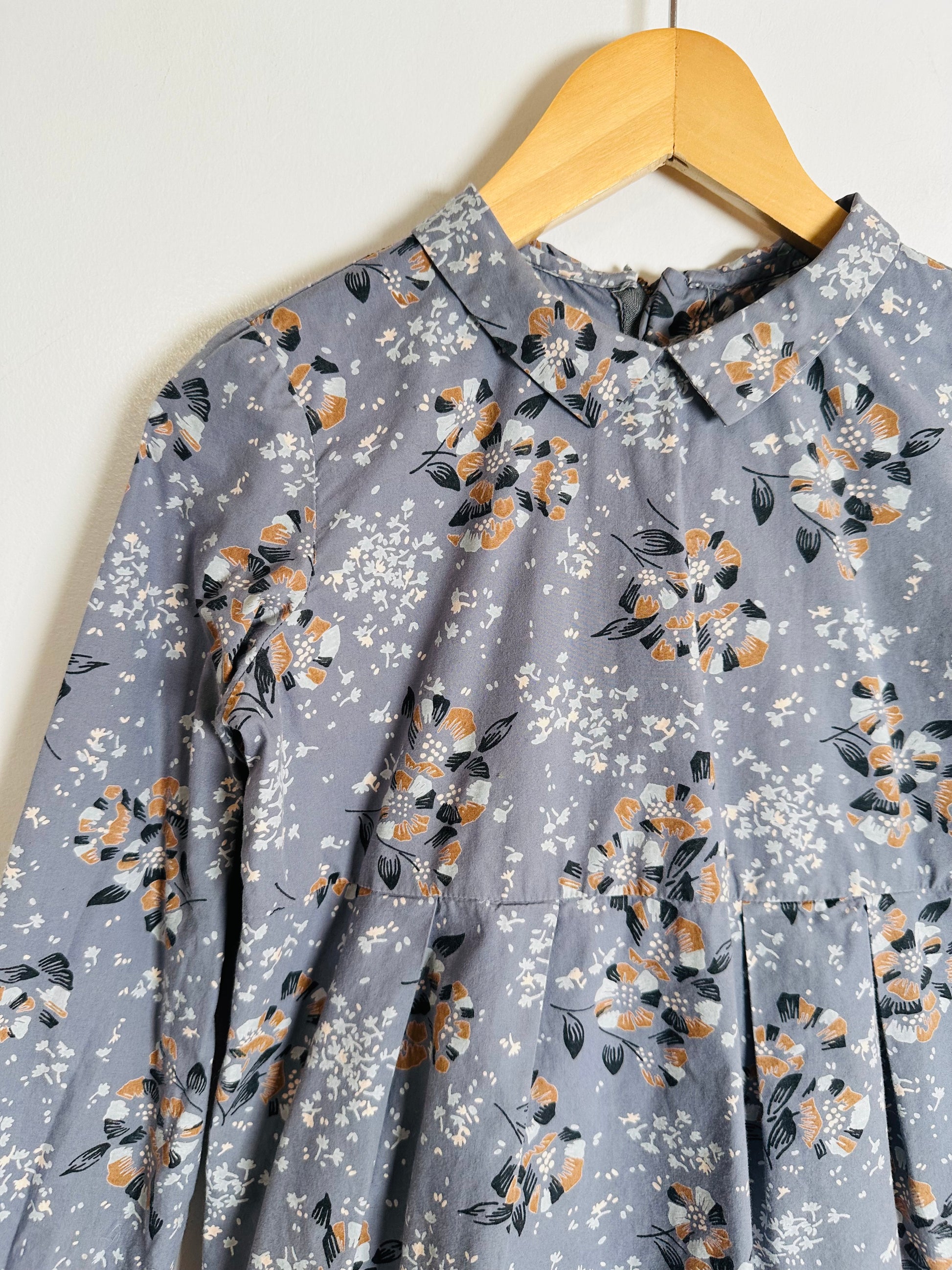 Floral-patterned blouse on a hanger against a white background