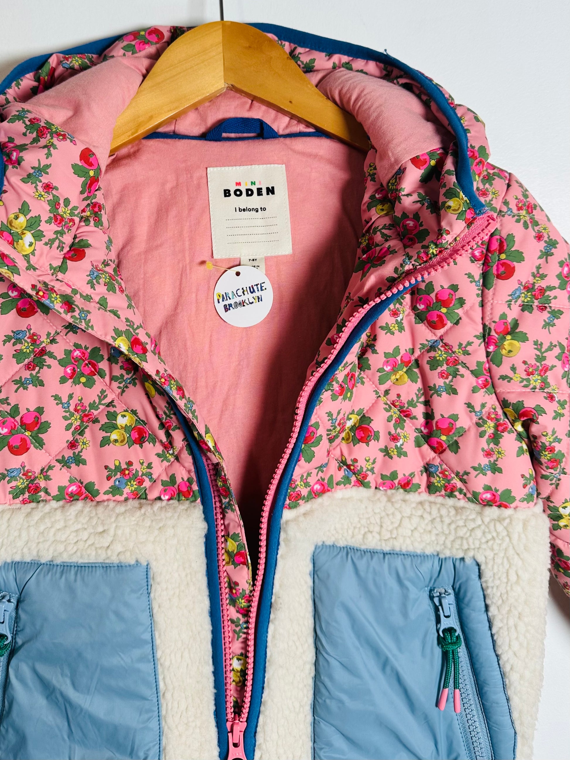 Pink floral jacket with a hanger on a white background