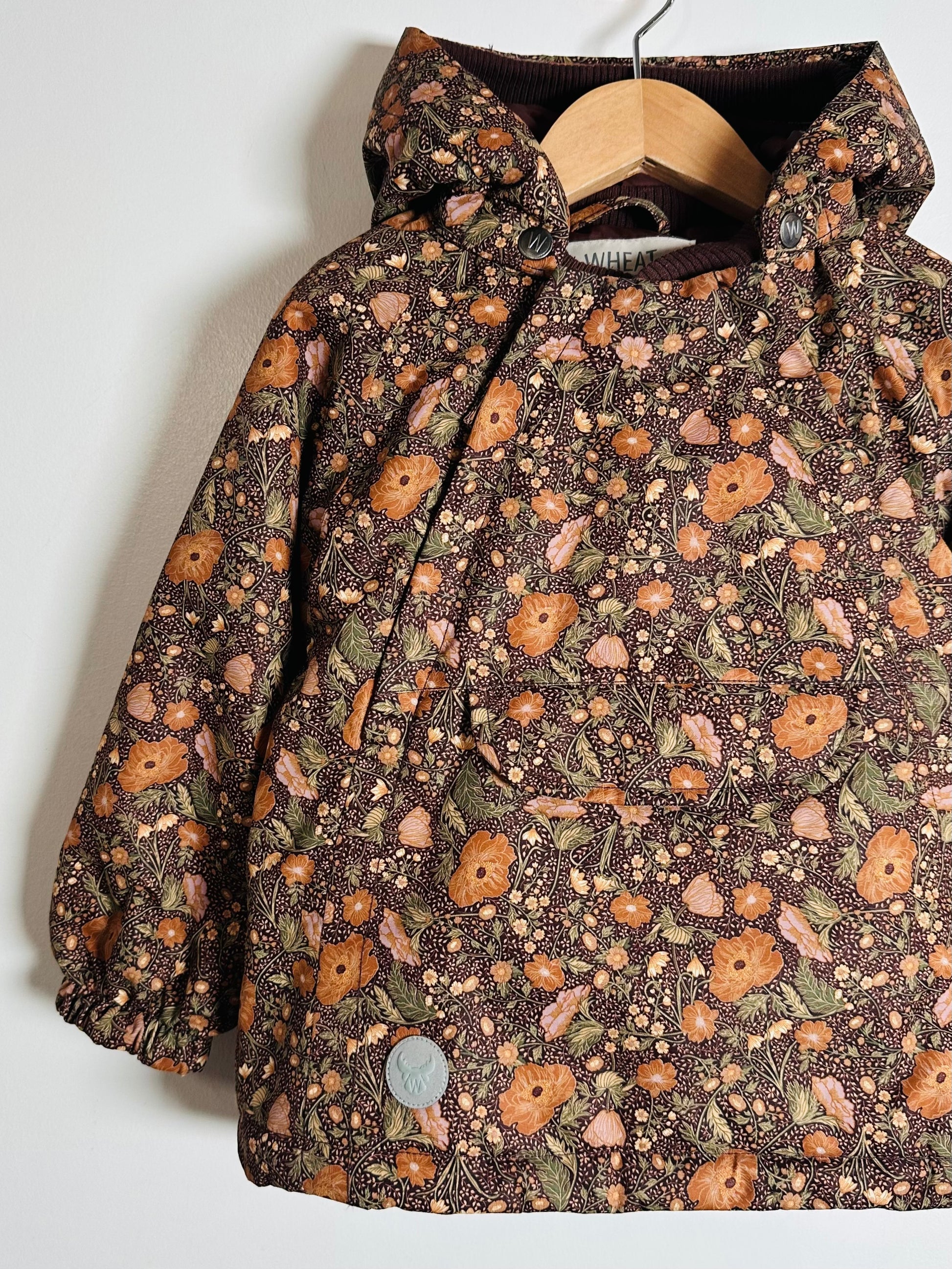 Floral-patterned jacket on a hanger against a white background