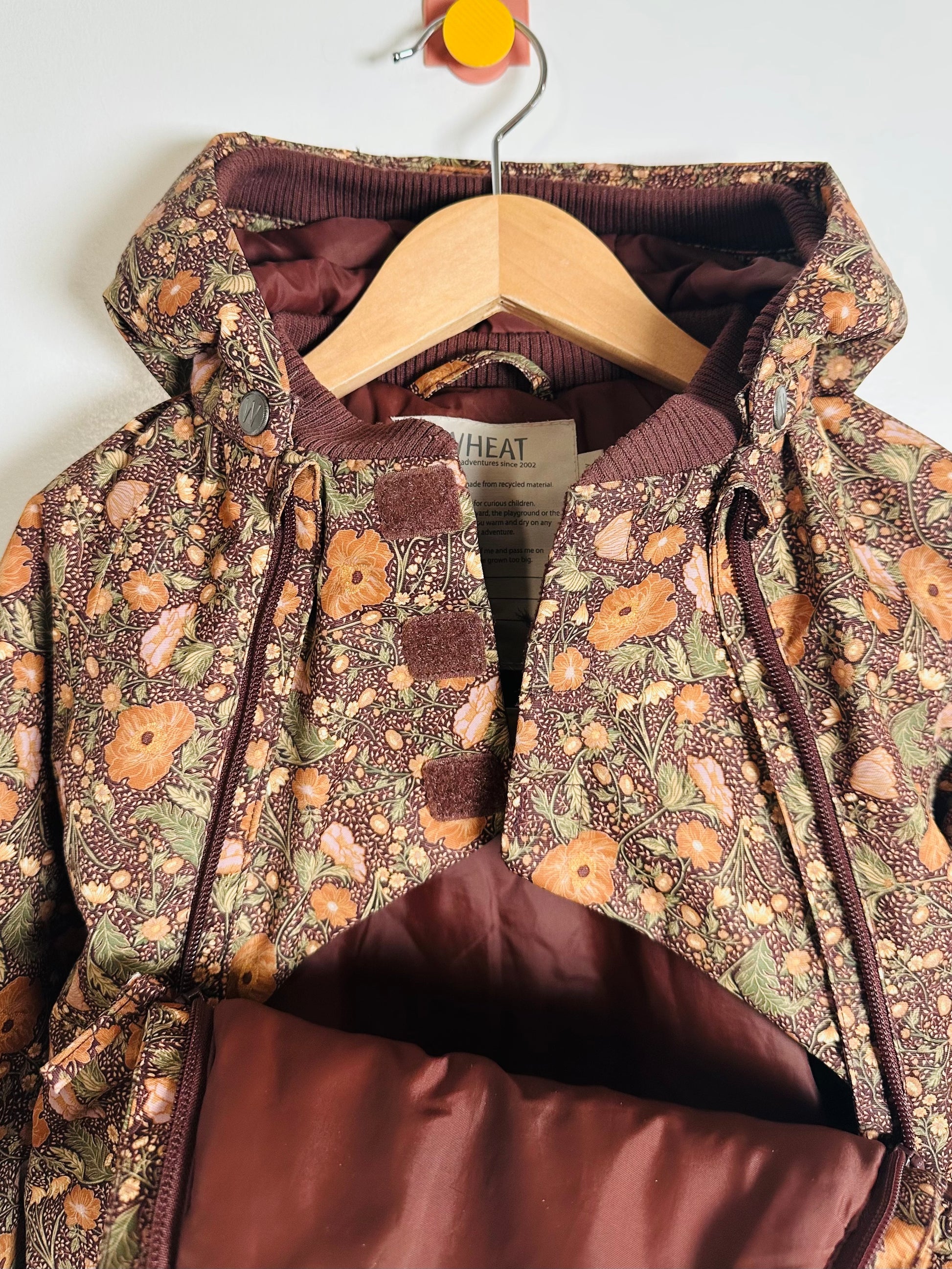 Floral-patterned jacket with a hood on a hanger against a white background