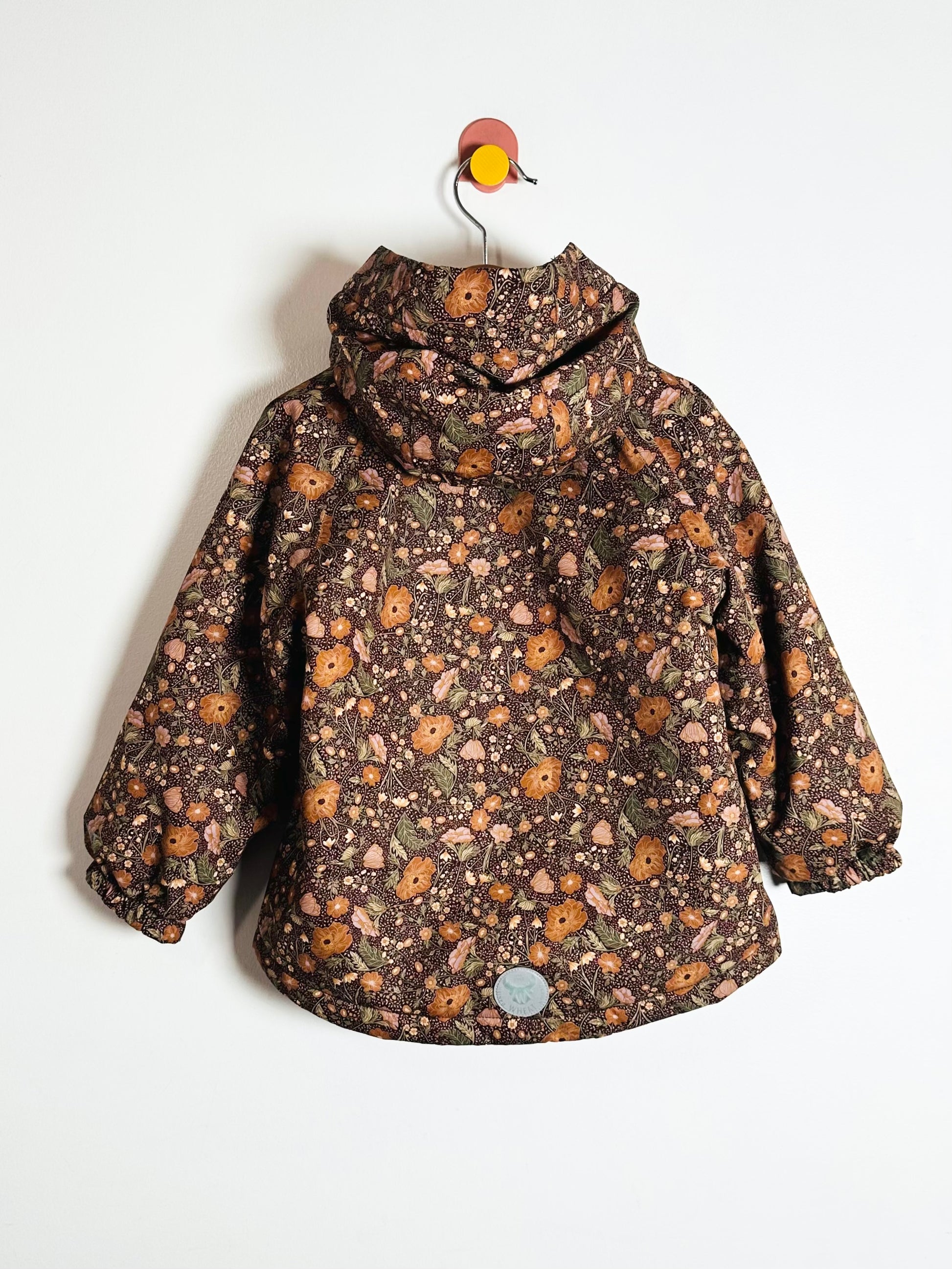 Floral-patterned jacket on a hanger against a white background
